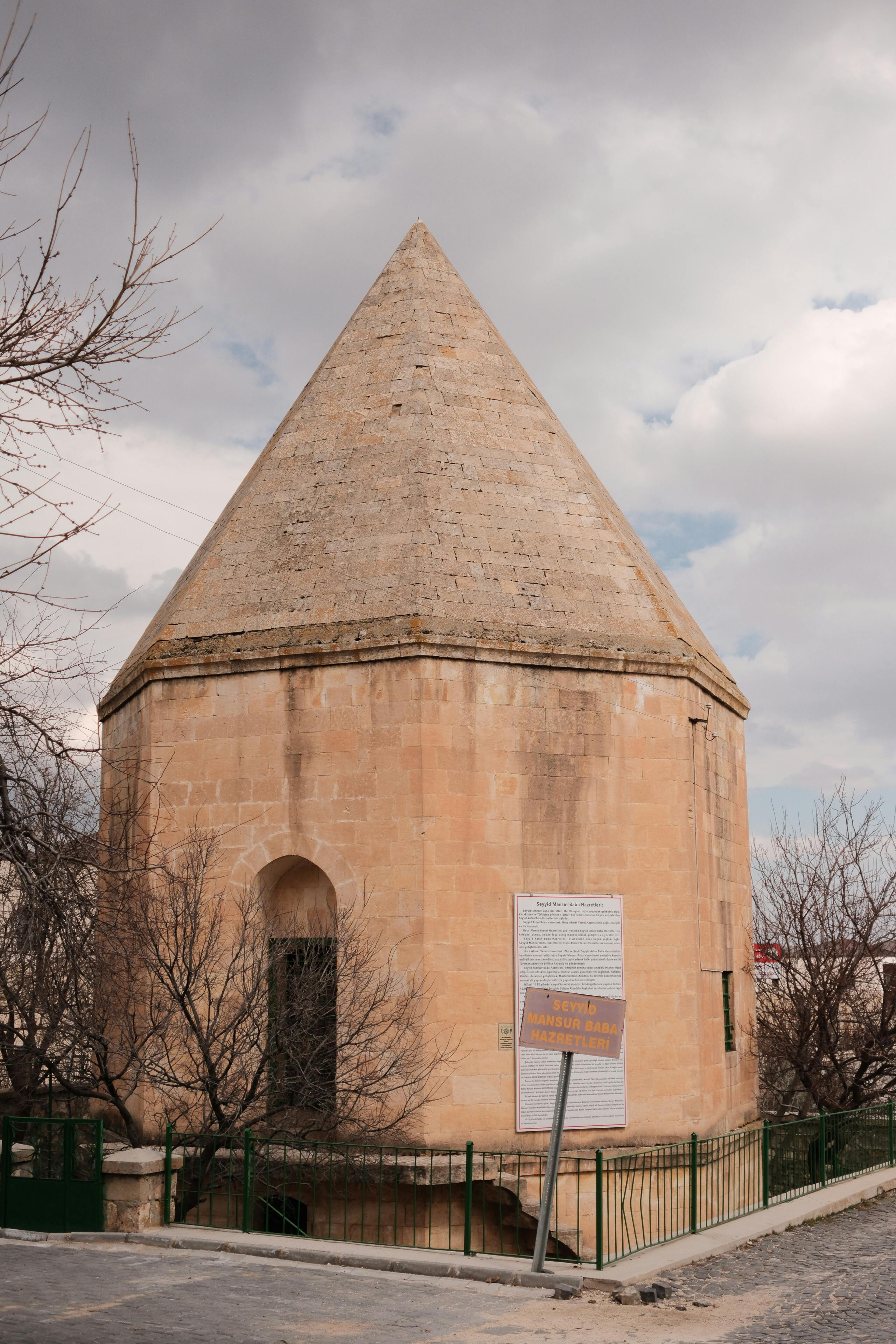 Δωρεάν Πέτρινο κτίριο με κωνική στέγη, περιτριγυρισμένο από γυμνά δέντρα κάτω από συννεφιασμένο ουρανό. Φωτογραφία από στοκ φωτογραφιών