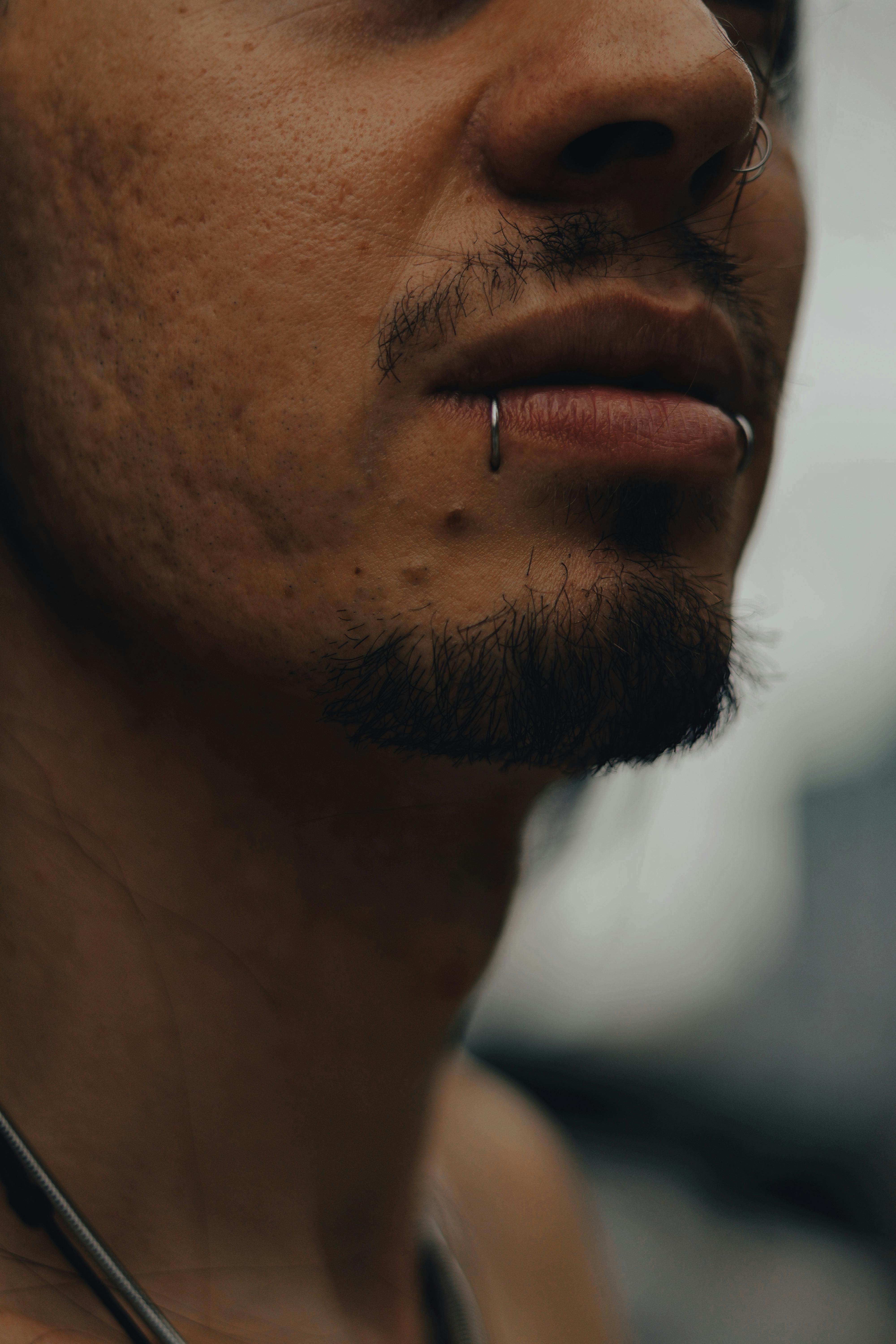 Δωρεάν Σαγηνευτικό κοντινό πλάνο των χειλιών ενός άνδρα με τρυπημένα και γένια που αγγίζουν τα γένια, που αναδεικνύει το μοναδικό του στυλ στο Σάο Πάολο. Φωτογραφία από στοκ φωτογραφιών