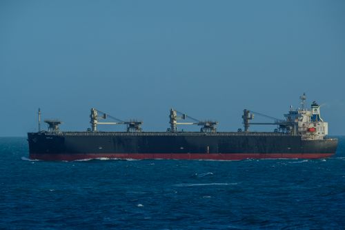 Free A large cargo ship sails through a vast, calm blue ocean under a clear sky, capturing maritime travel. Stock Photo