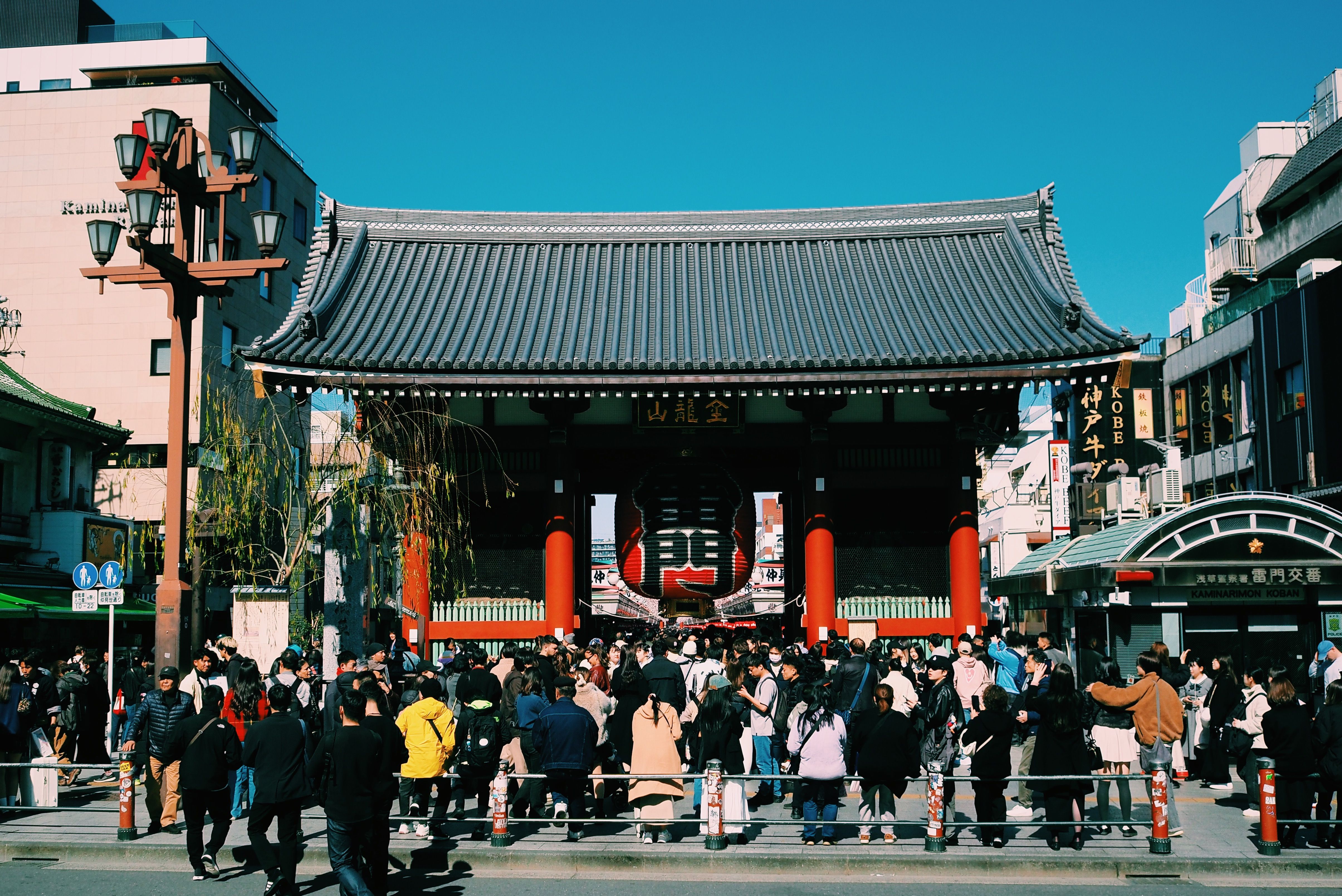 Free Large crowd gathers at the iconic Senso-ji Temple gate in Tokyo, Japan, under a clear blue sky. Stock Photo