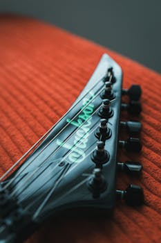Detailed view of an electric guitar headstock resting on a textured red fabric.