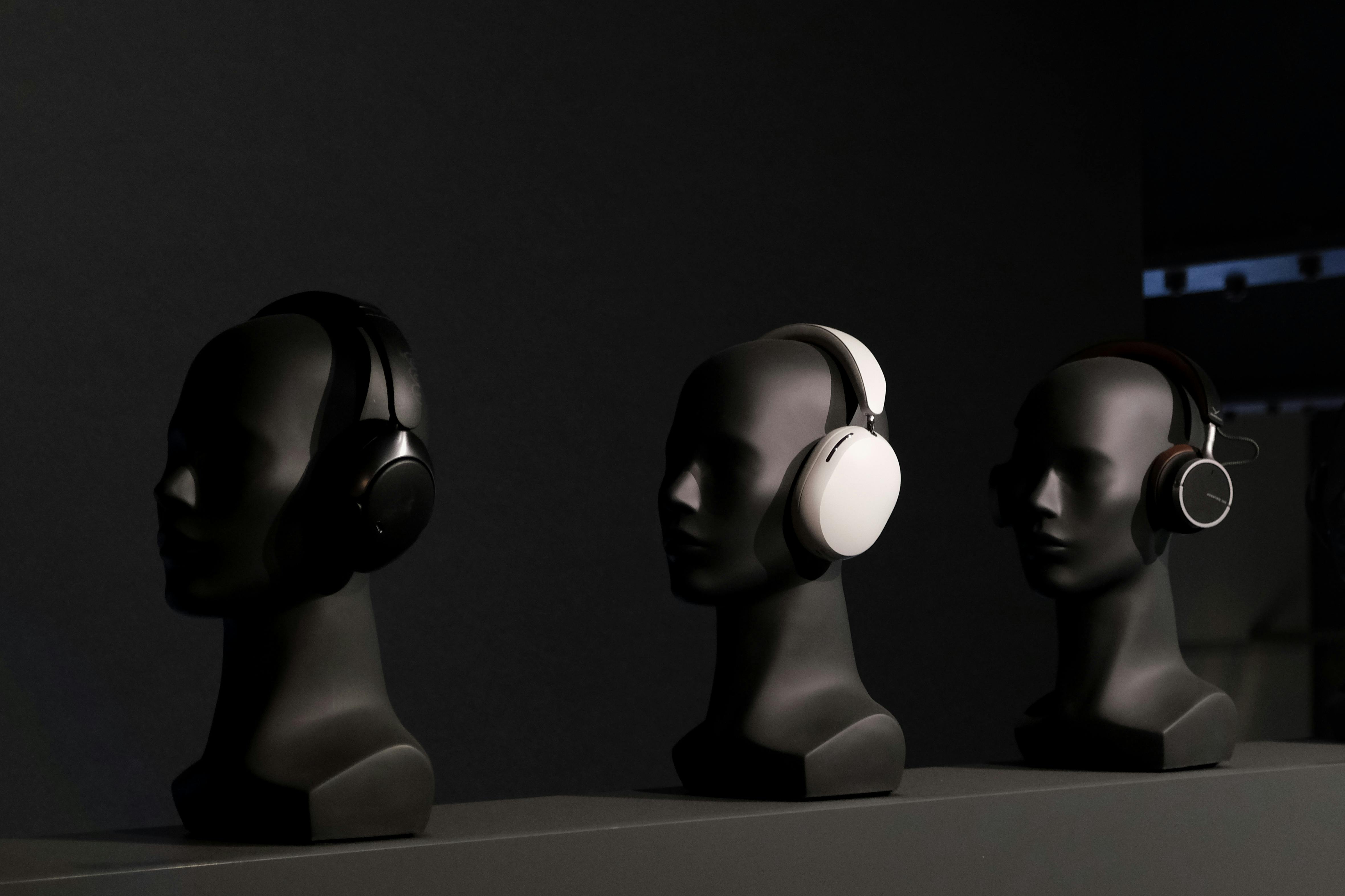 Free Three mannequins showcasing modern black and white headphones in a sleek, artistic arrangement. Stock Photo