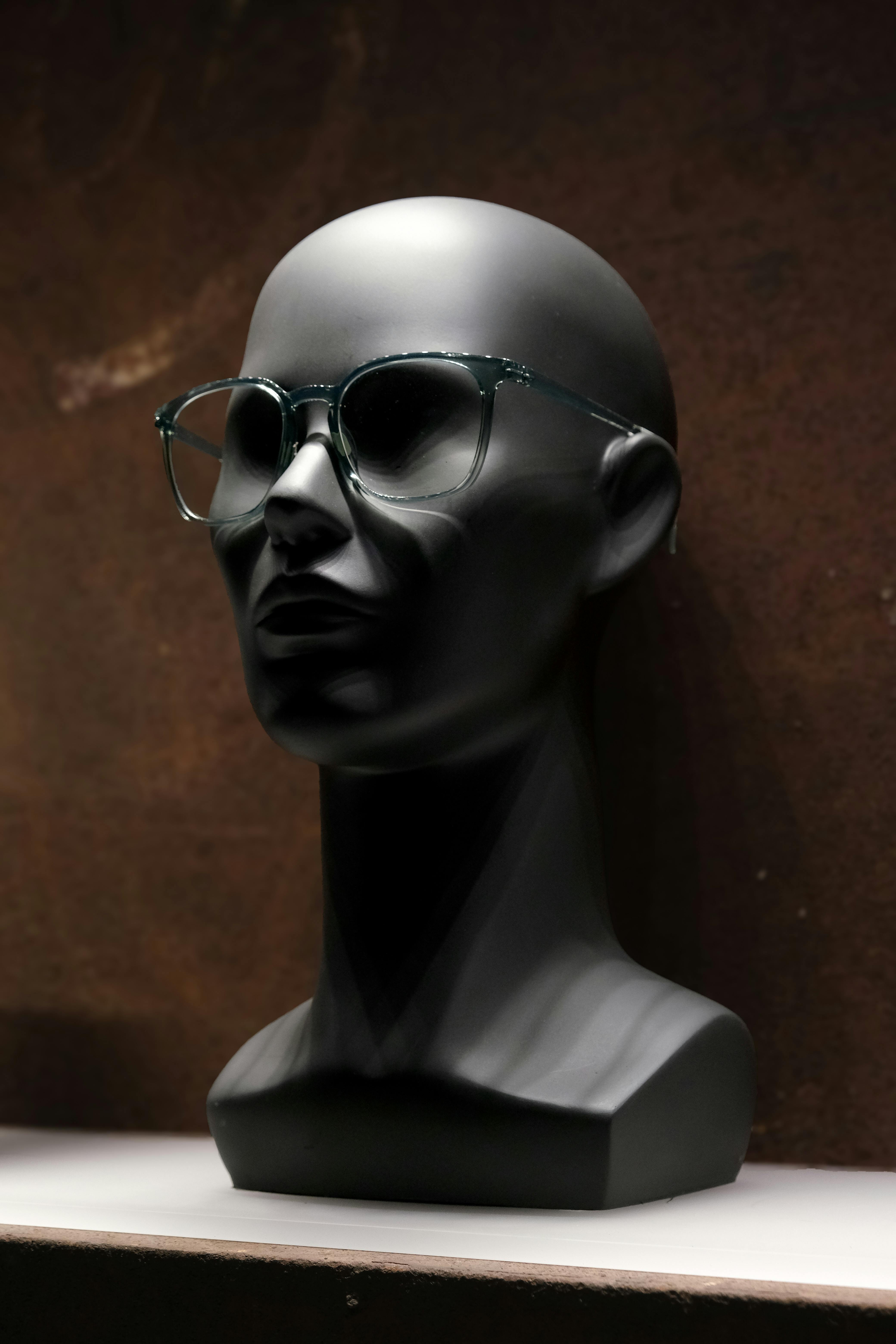 Gratis Svart utstillingsdukkehode med briller mot mørk bakgrunn, som viser frem moderne brillestil. Arkivbilde