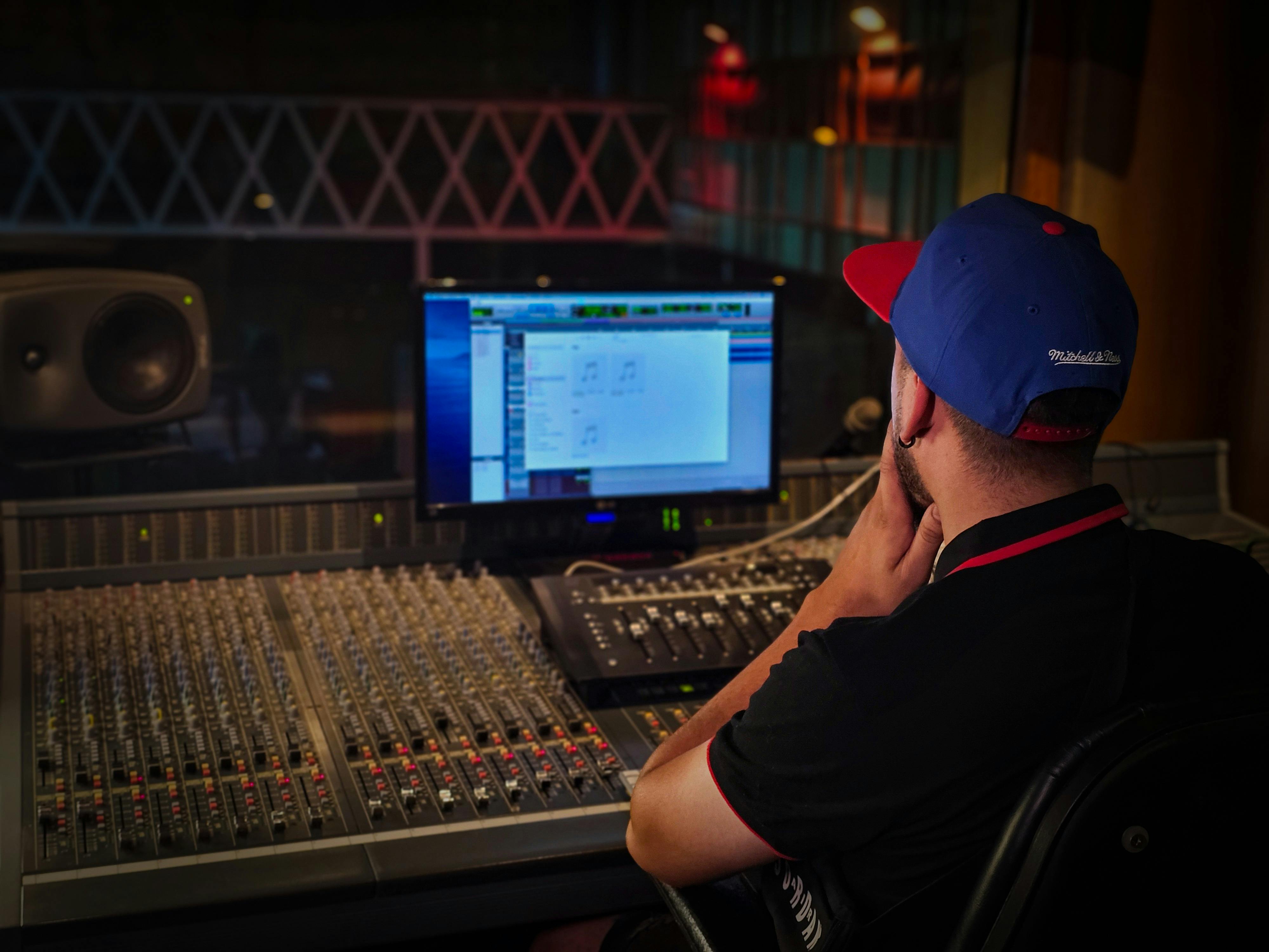 Kostenlos Toningenieur arbeitet an einem Mischpult in einem gemütlichen Aufnahmestudio mit stimmungsvoller Beleuchtung. Stock-Foto