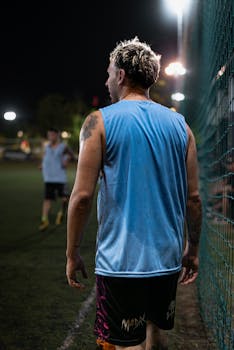 Soccer player on field during a night game, dressed in sports attire, ready for action.
