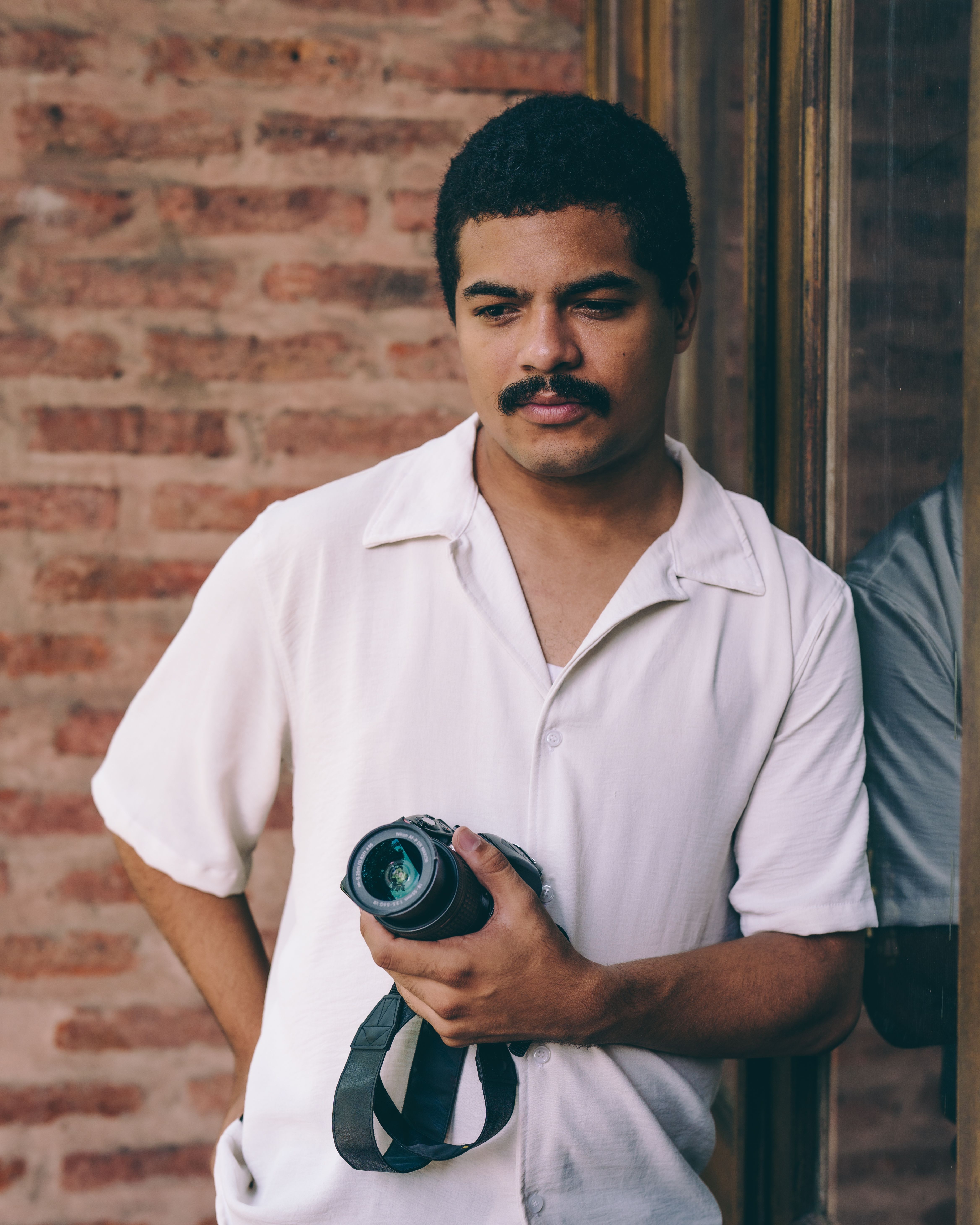 Man with camera reflecting by a window, capturing introspection