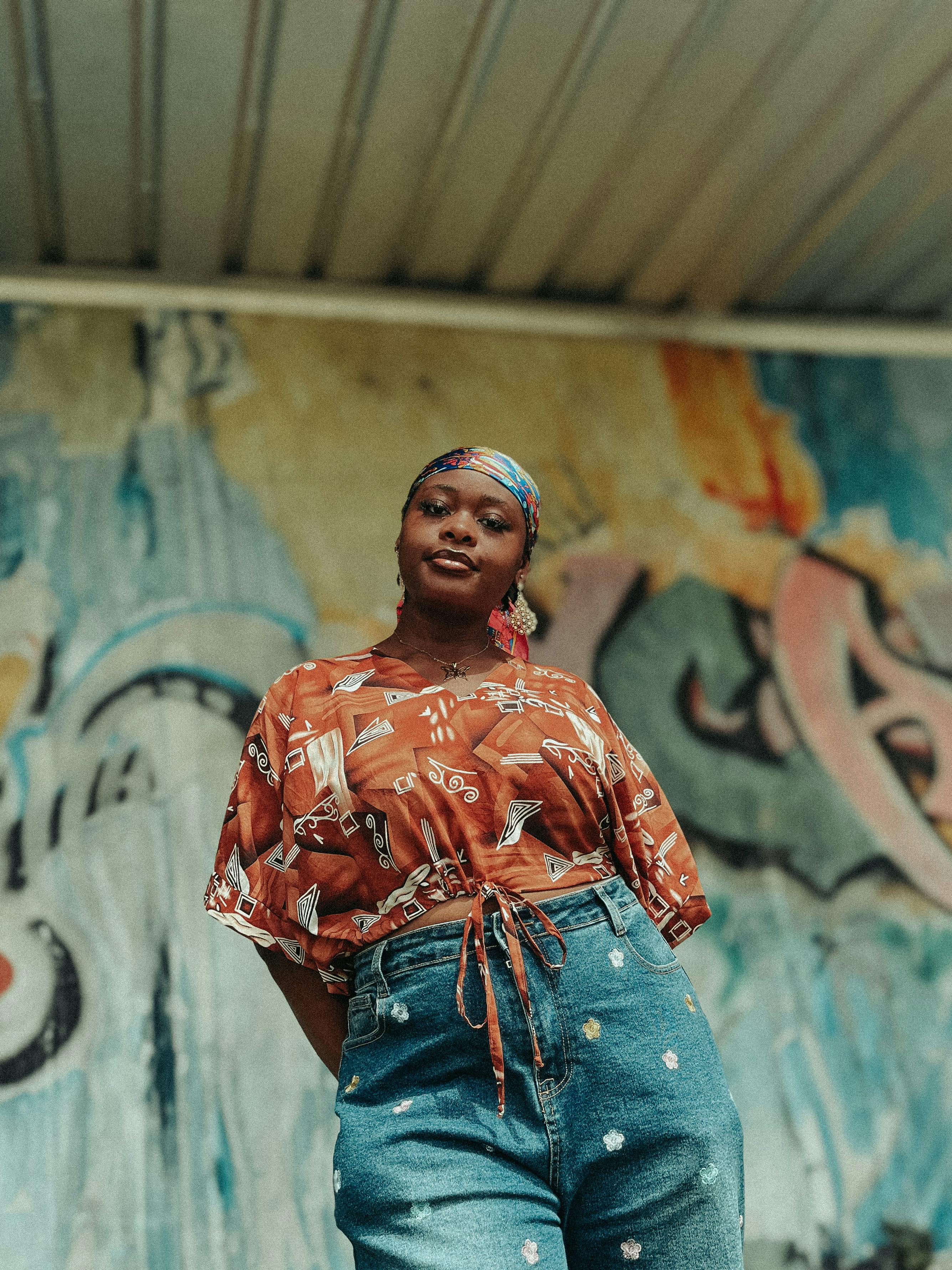 Kostenlos Selbstbewusste Frau posiert im Freien vor einem farbenfrohen urbanen Street-Art-Wandgemälde. Stock-Foto