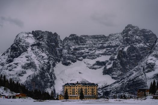 Scenic view of a grand hotel amidst the snow-covered Dolomites in winter.