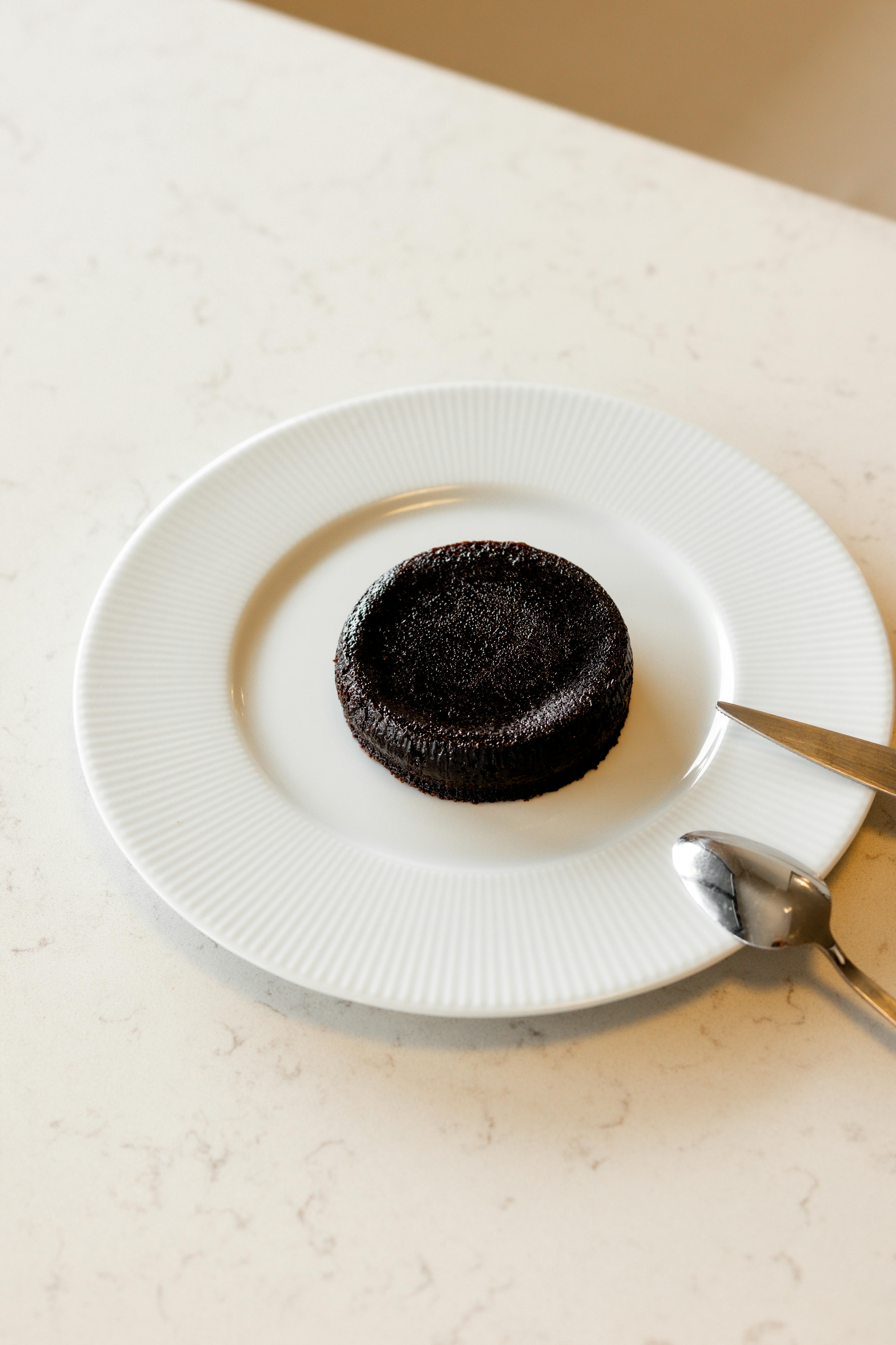 Kostenlos Gönnen Sie sich einen reichhaltigen Schokoladen-Lava-Kuchen, der elegant auf einem weißen Teller serviert wird. Stock-Foto