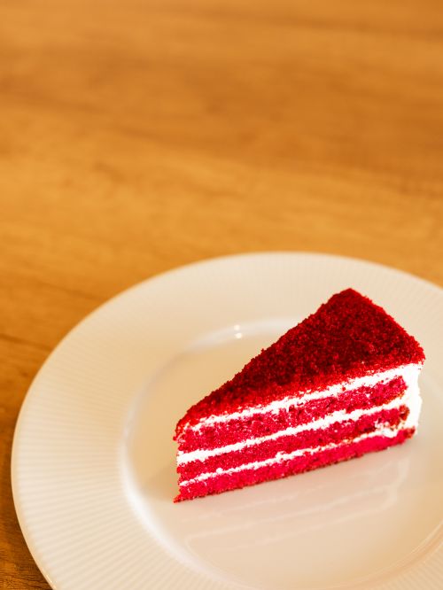 Free Delicious slice of red velvet cake with cream layers on a white plate. Stock Photo
