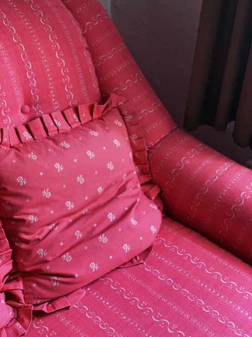 Free A charming red armchair with a ruffled pillow adds a touch of elegance to the room. Stock Photo