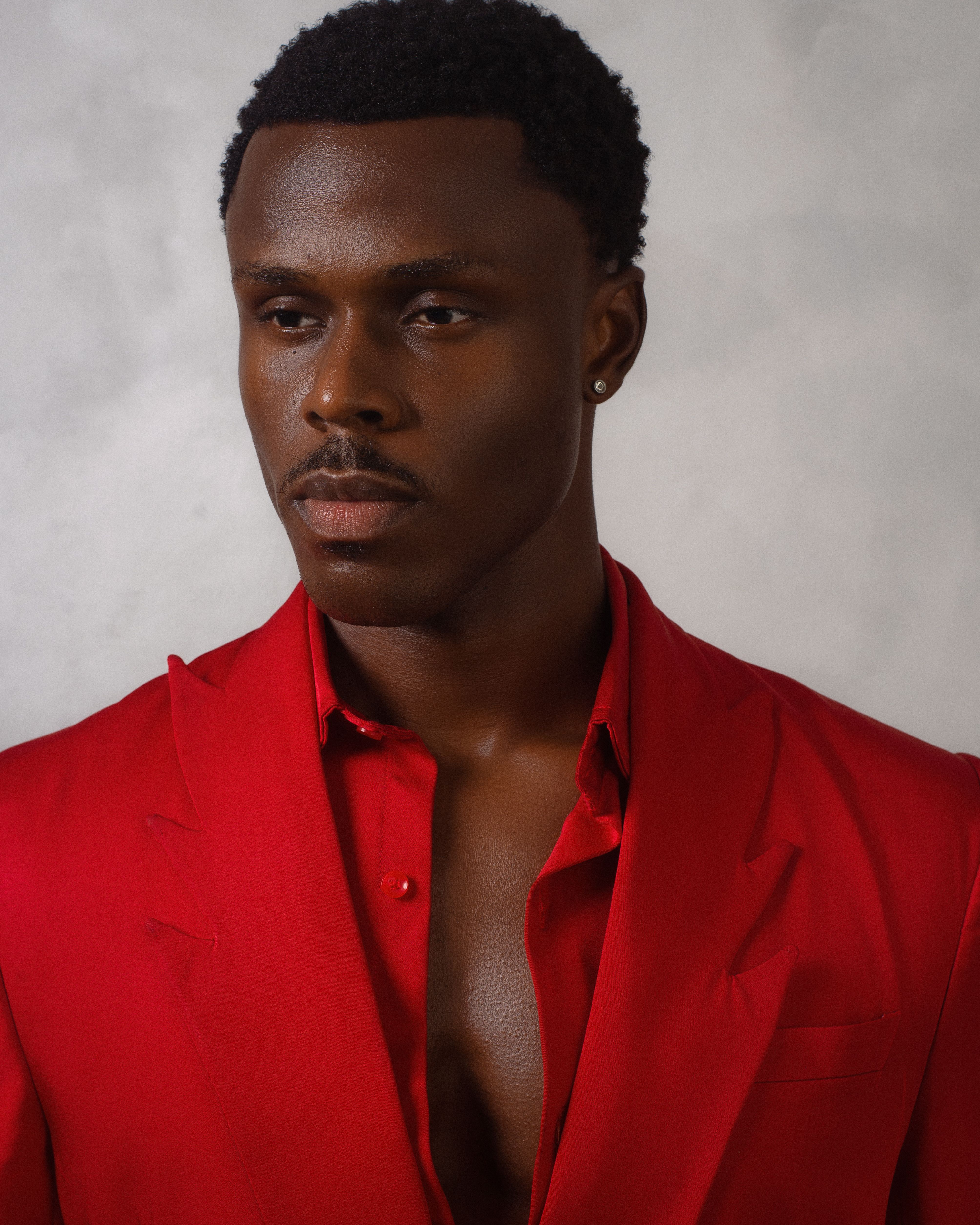 Stylish portrait of a man wearing a red suit with a soft white background.