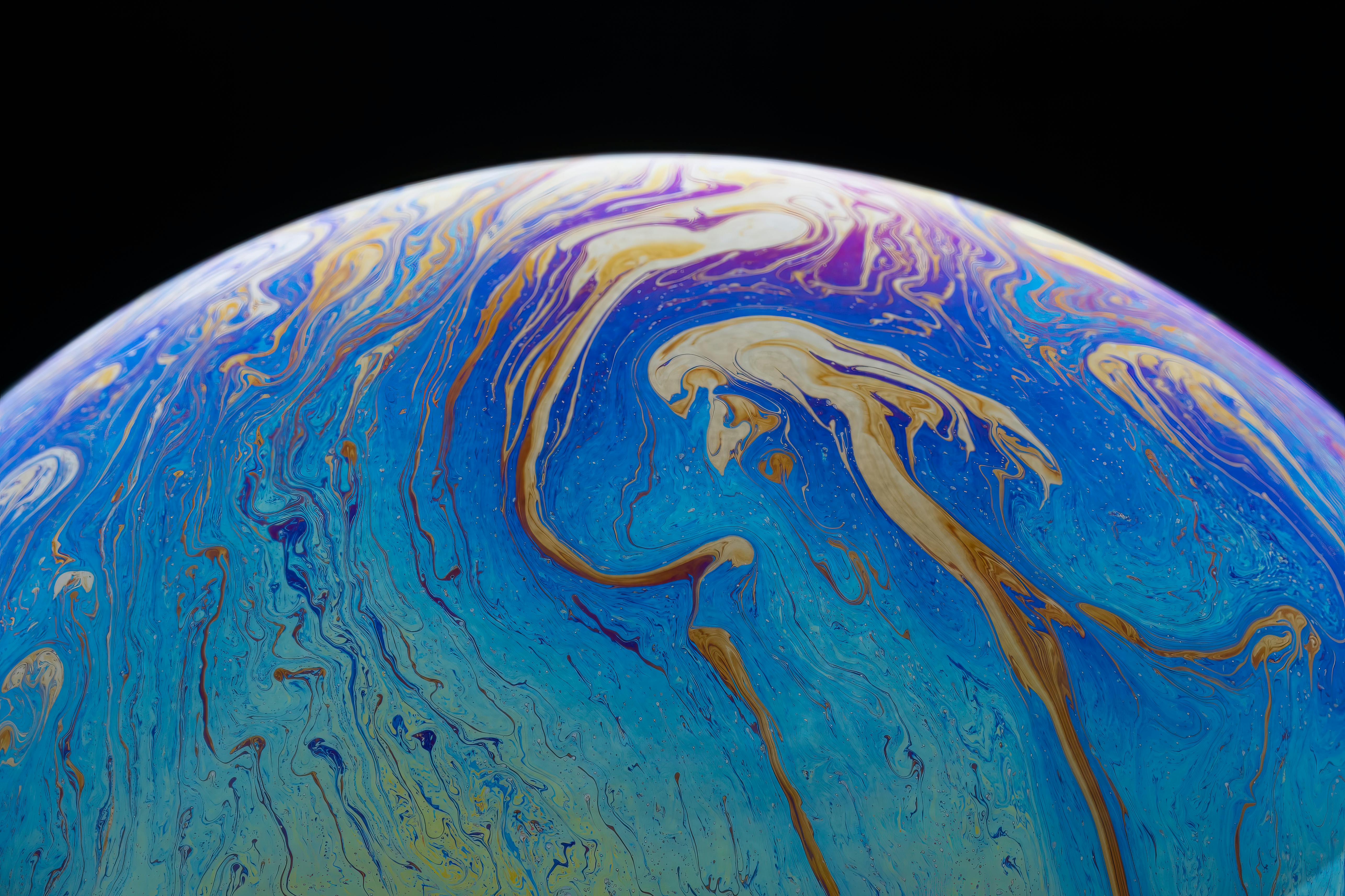 Gratis Toma de primer plano de una colorida burbuja de jabón iridiscente con textura fluida sobre un fondo oscuro. Foto de stock