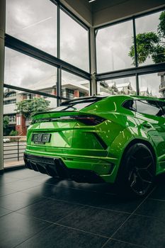 Vibrant green sports car displayed in a modern showroom with urban backdrop.