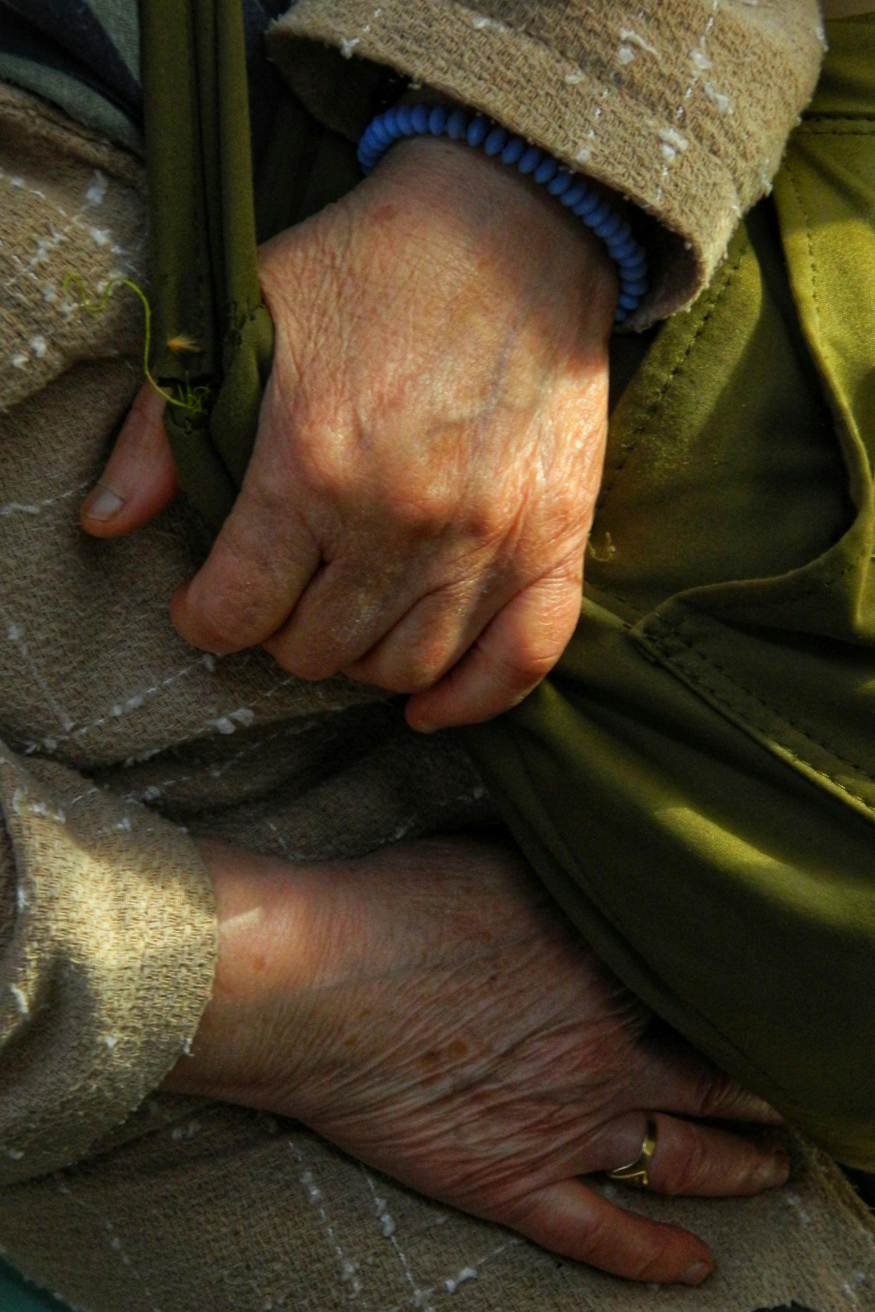 Kostenlos Detaillierte Nahaufnahme von älteren Händen, die auf einer Tasche ruhen und Alter und Erfahrung verdeutlichen. Stock-Foto