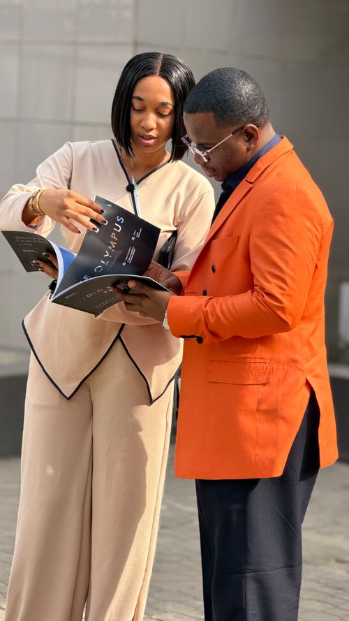 Free A man and woman in professional attire discussing a magazine outside on a sunny day. Stock Photo