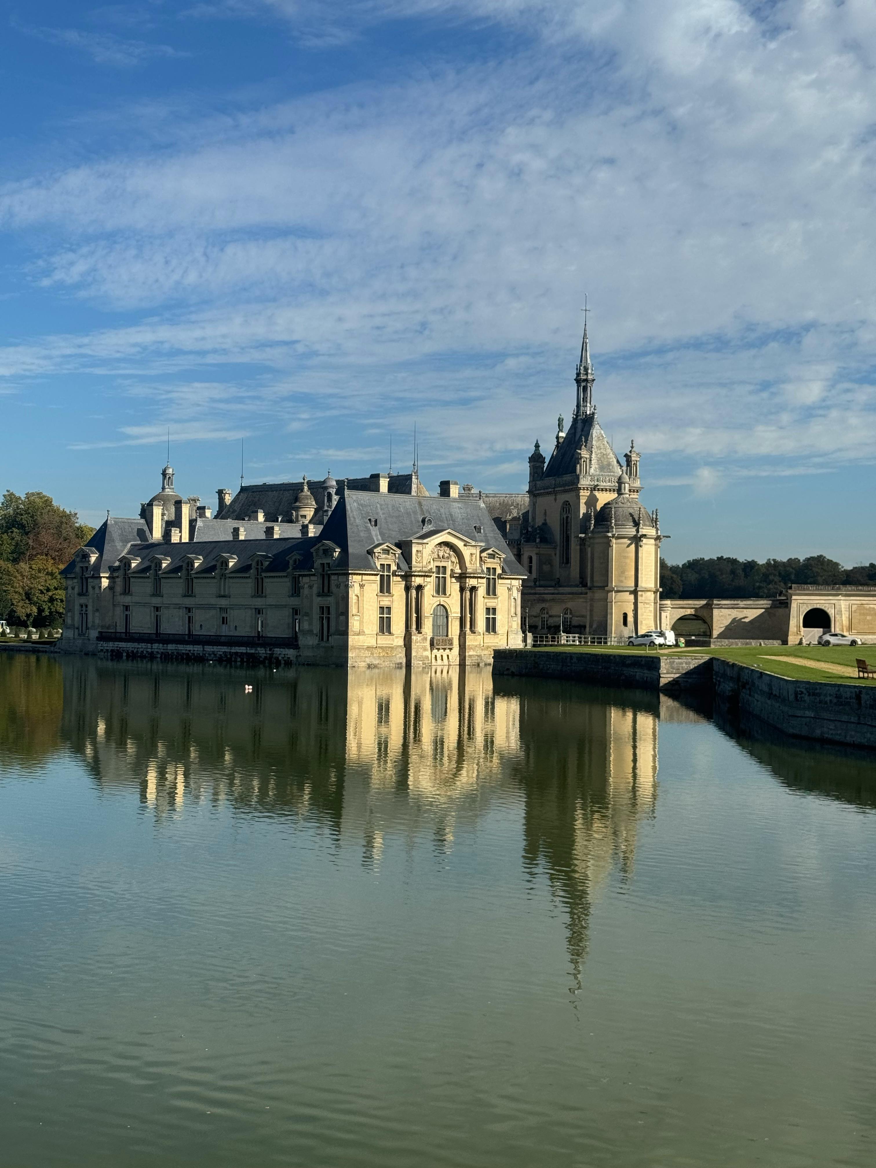 Kostenlos Ein atemberaubendes französisches Schloss mit Renaissance-Architektur, das sich in einem ruhigen See spiegelt, umgeben von Natur. Stock-Foto