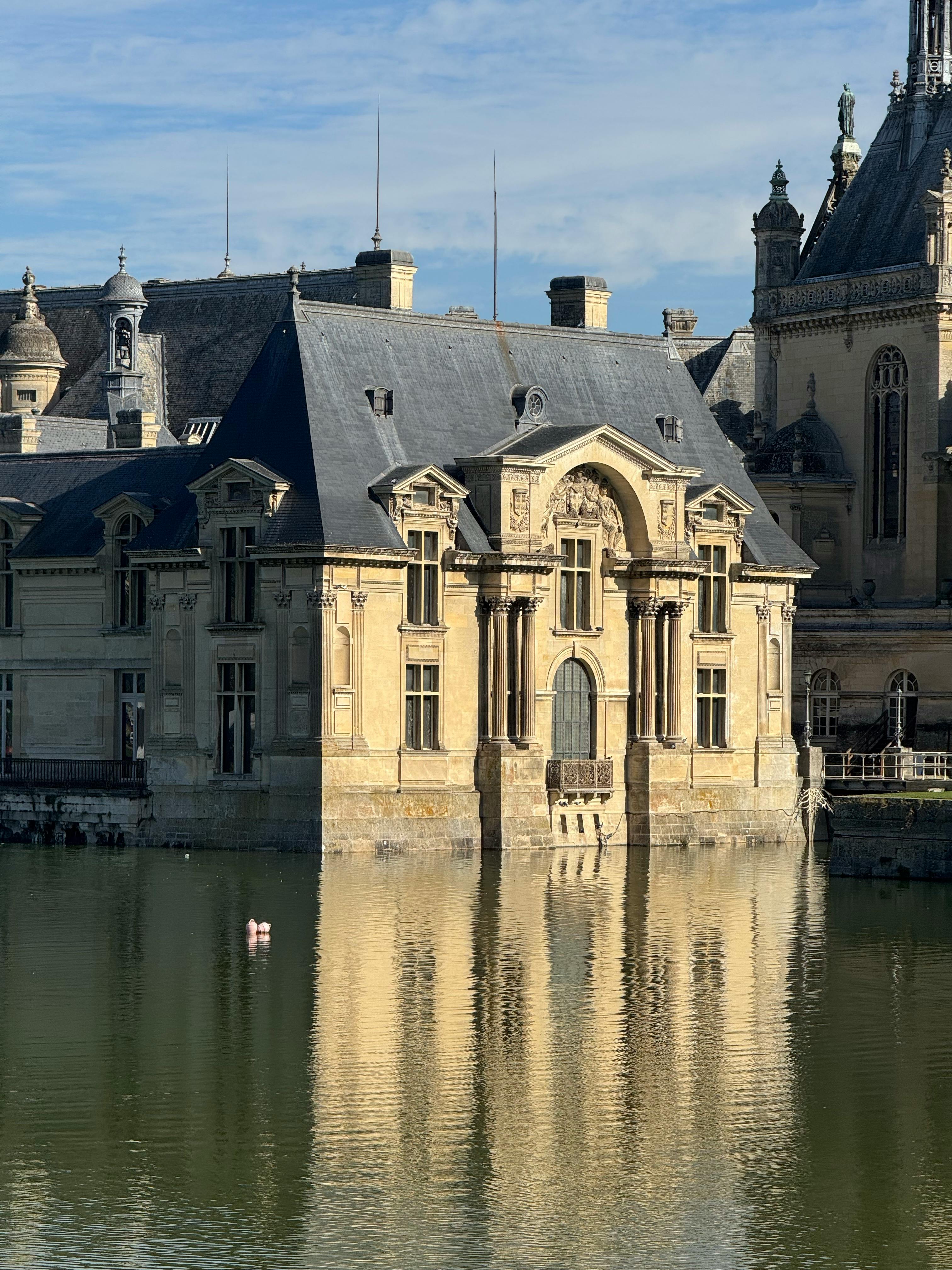 Kostenlos Die historische Fassade des Schlosses Chantilly spiegelt sich in einem ruhigen See in Frankreich. Stock-Foto