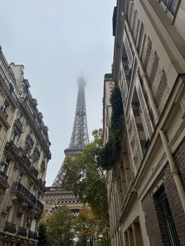 A misty morning view of the Eiffel Tower from a classic Parisian street.