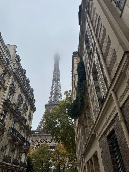 Free A misty morning view of the Eiffel Tower from a classic Parisian street. Stock Photo