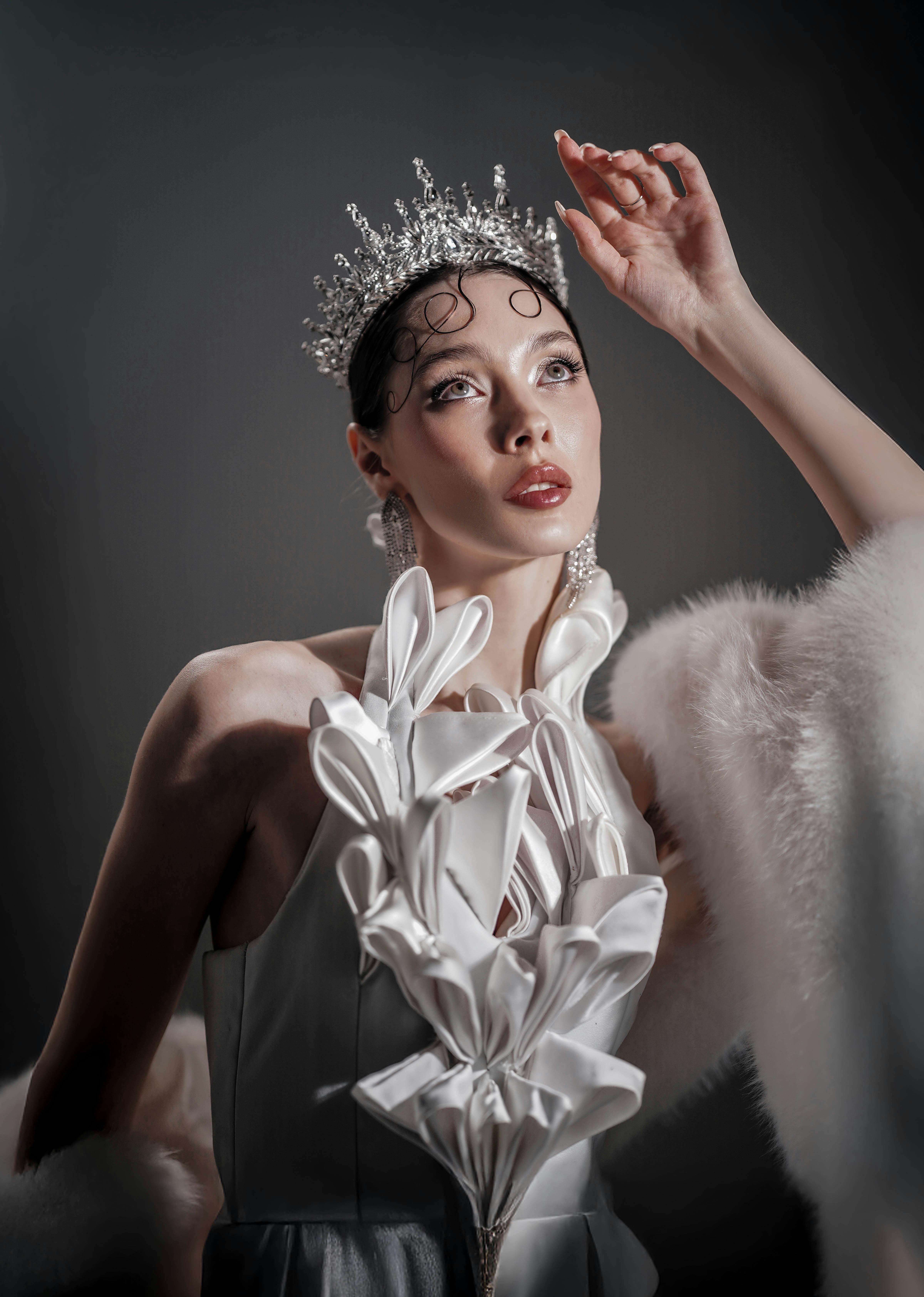 Kostenlos Elegante Frau in Krone und weißem Gewand, die Charme und Raffinesse ausstrahlt. Stock-Foto