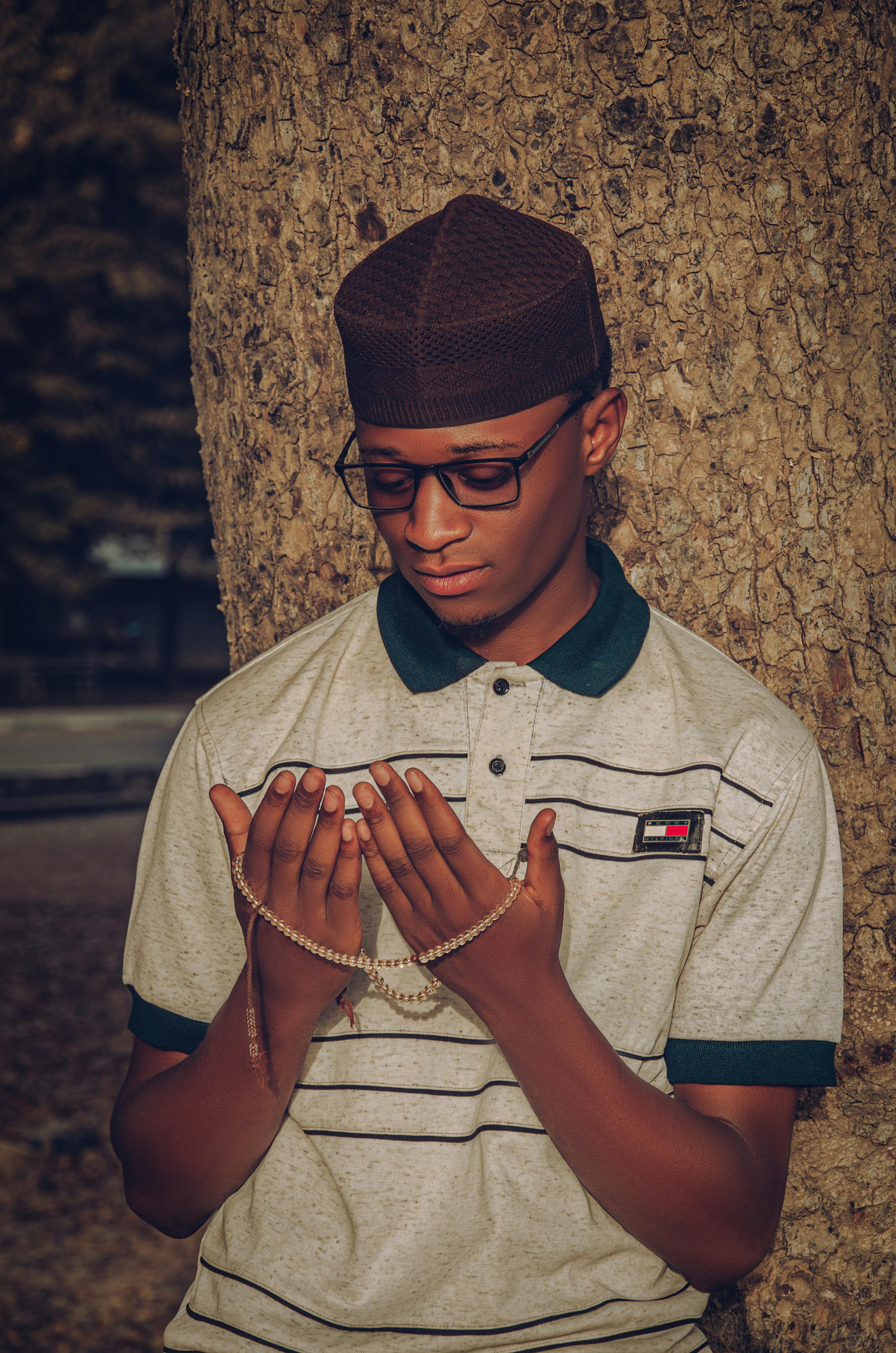 Kostenlos Junger Mann betet im Freien, hält Gebetsperlen in den Händen, voller Ruhe und Konzentration. Stock-Foto