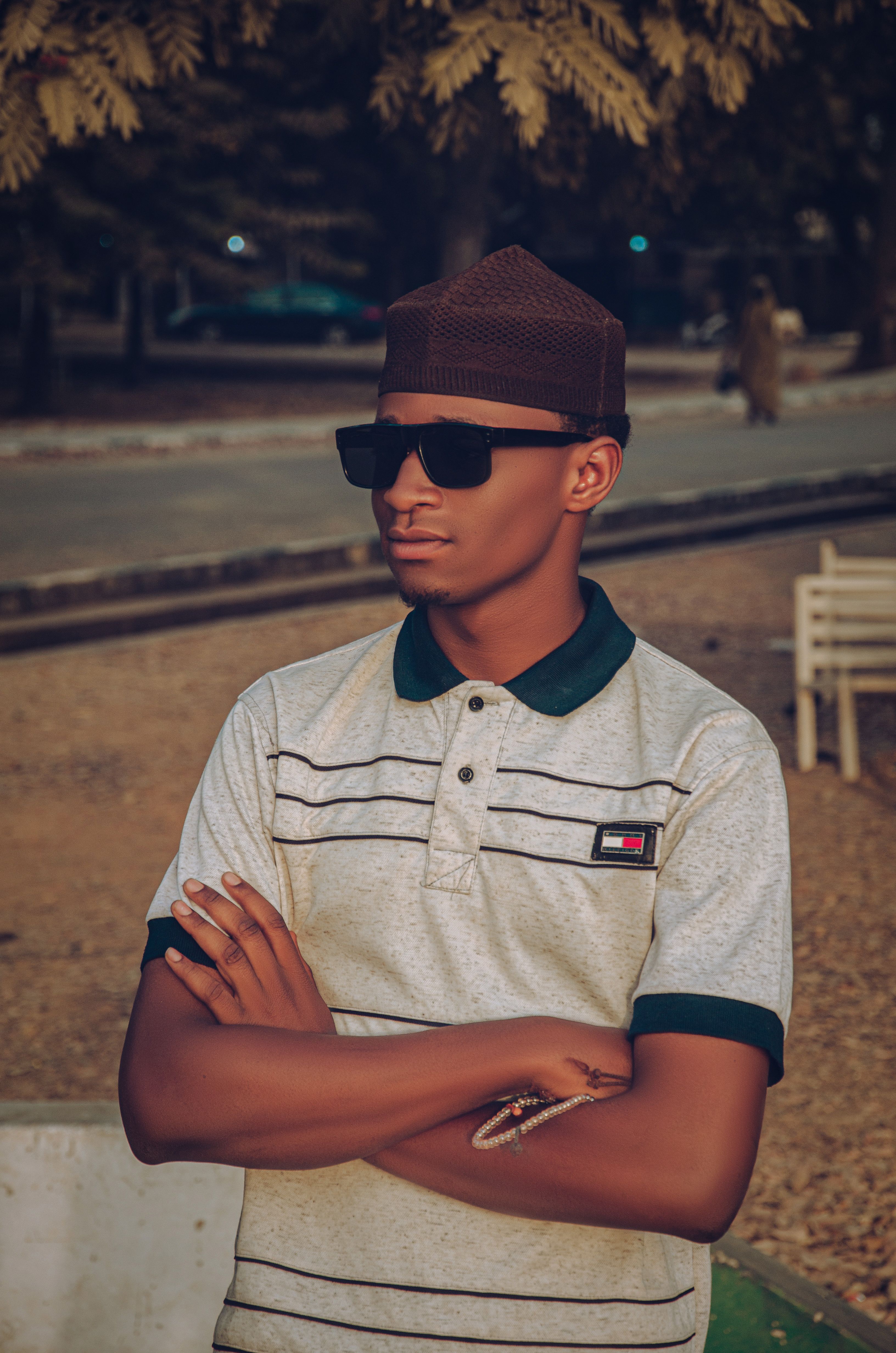Young man in casual attire with sunglasses outdoors in a relaxed pose.