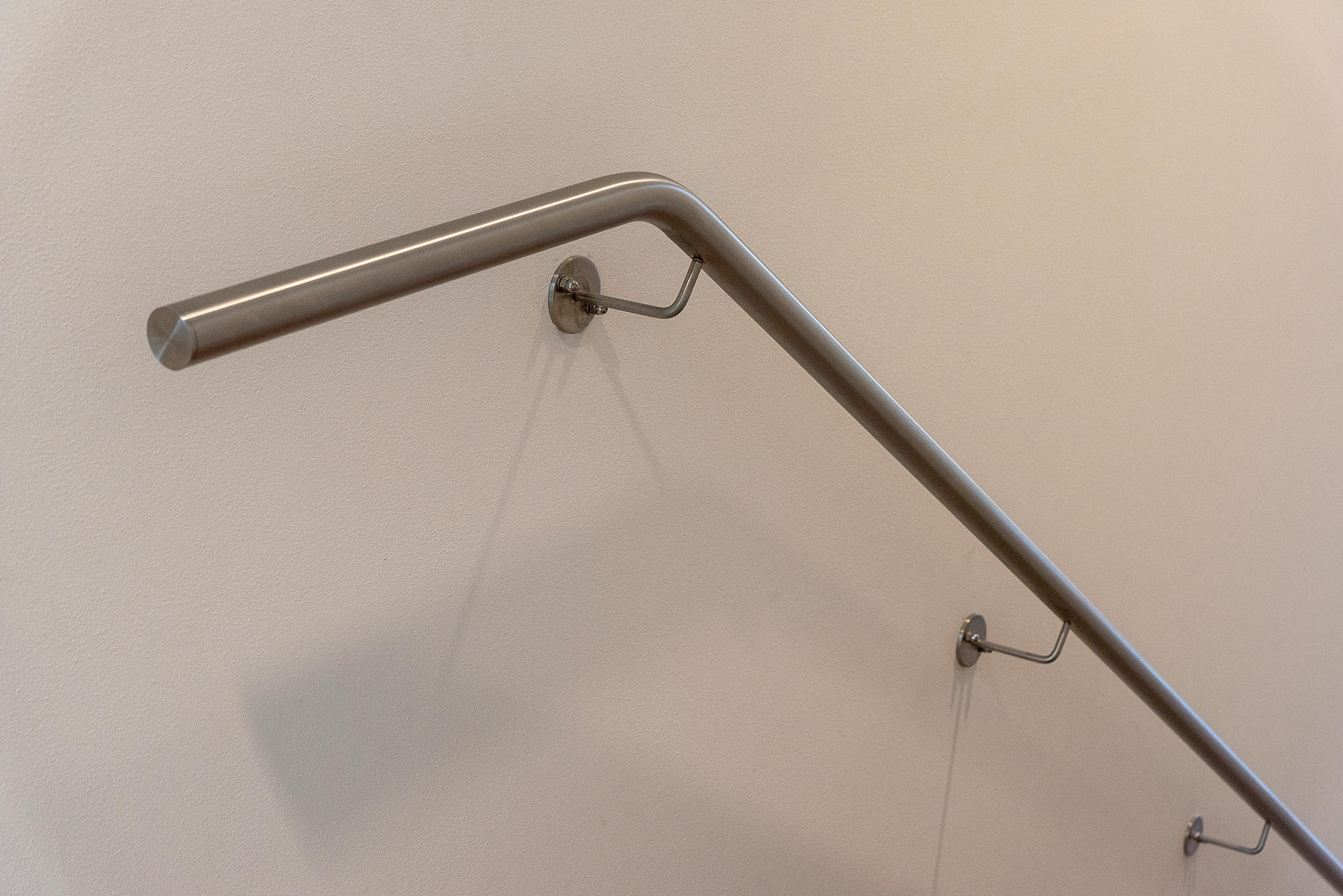 Gratis Nærbilde av et elegant rekkverk i rustfritt stål på en beige vegg, ideelt for moderne interiør. Arkivbilde