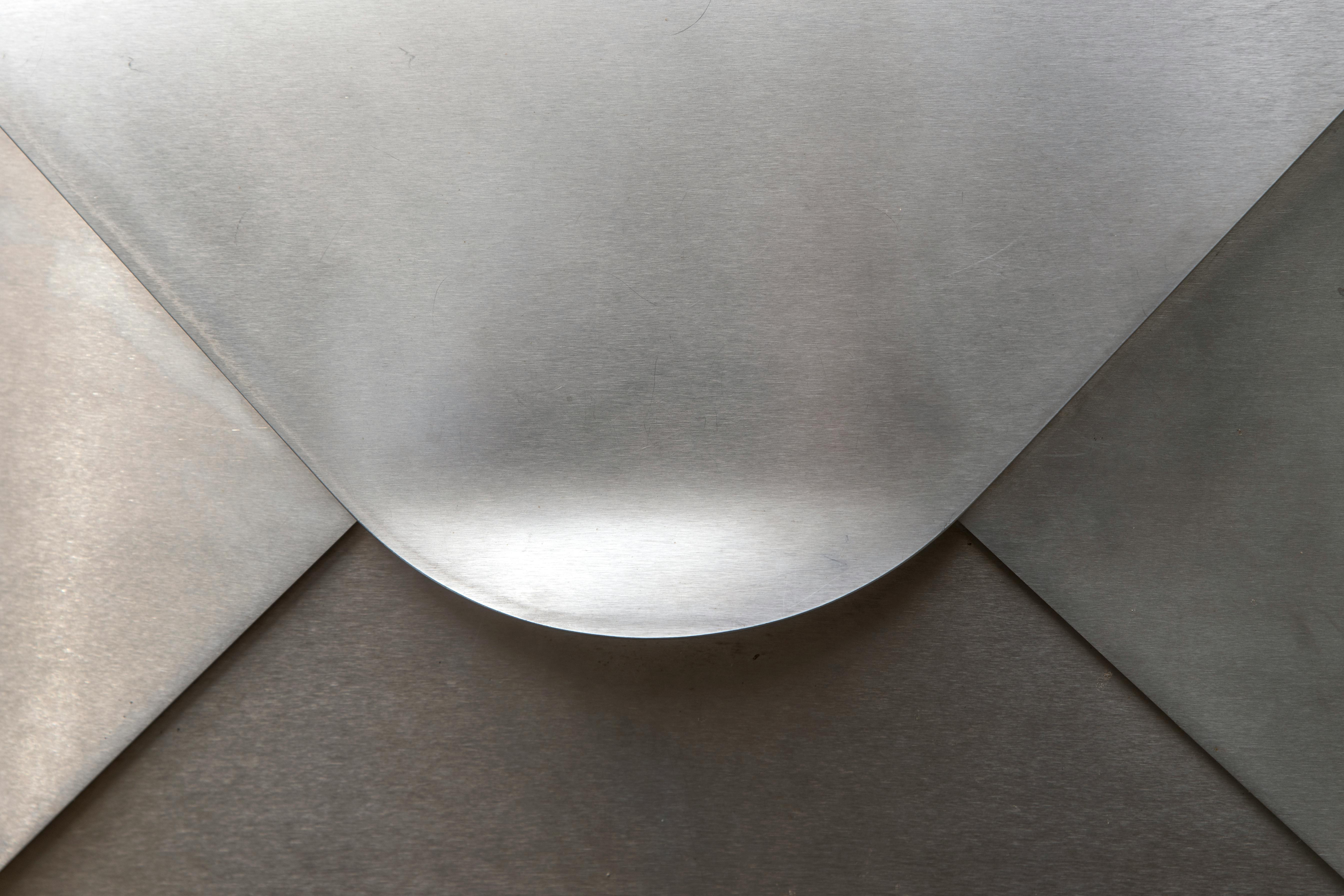 gratis Detailopname van een zilverkleurige, metallic envelop met elegante rondingen en texturen. Stockfoto
