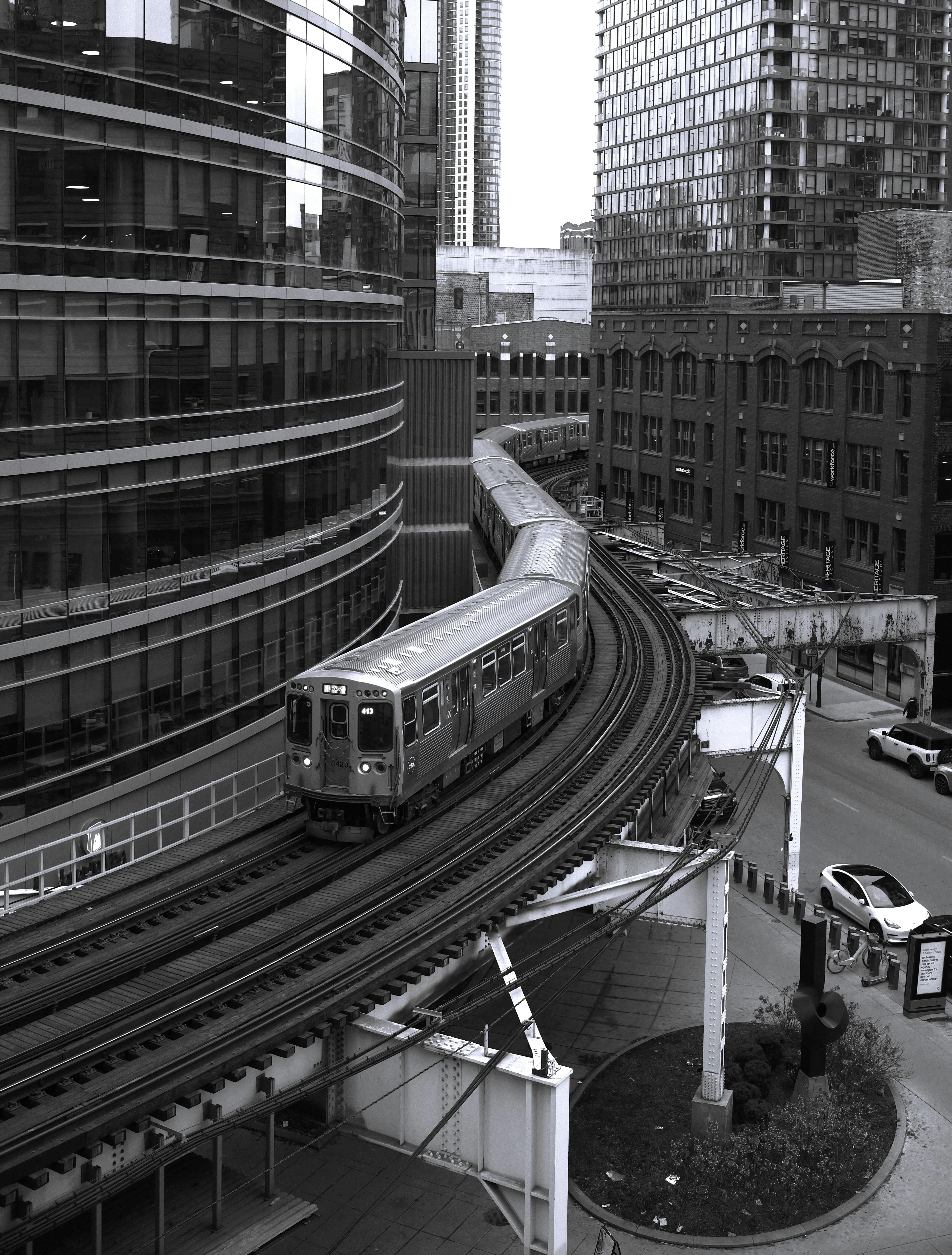 бесплатная Черно-белая фотография поезда линии L в Чикаго, проходящего поворот в центре города, штат Иллинойс. Стоковое фото