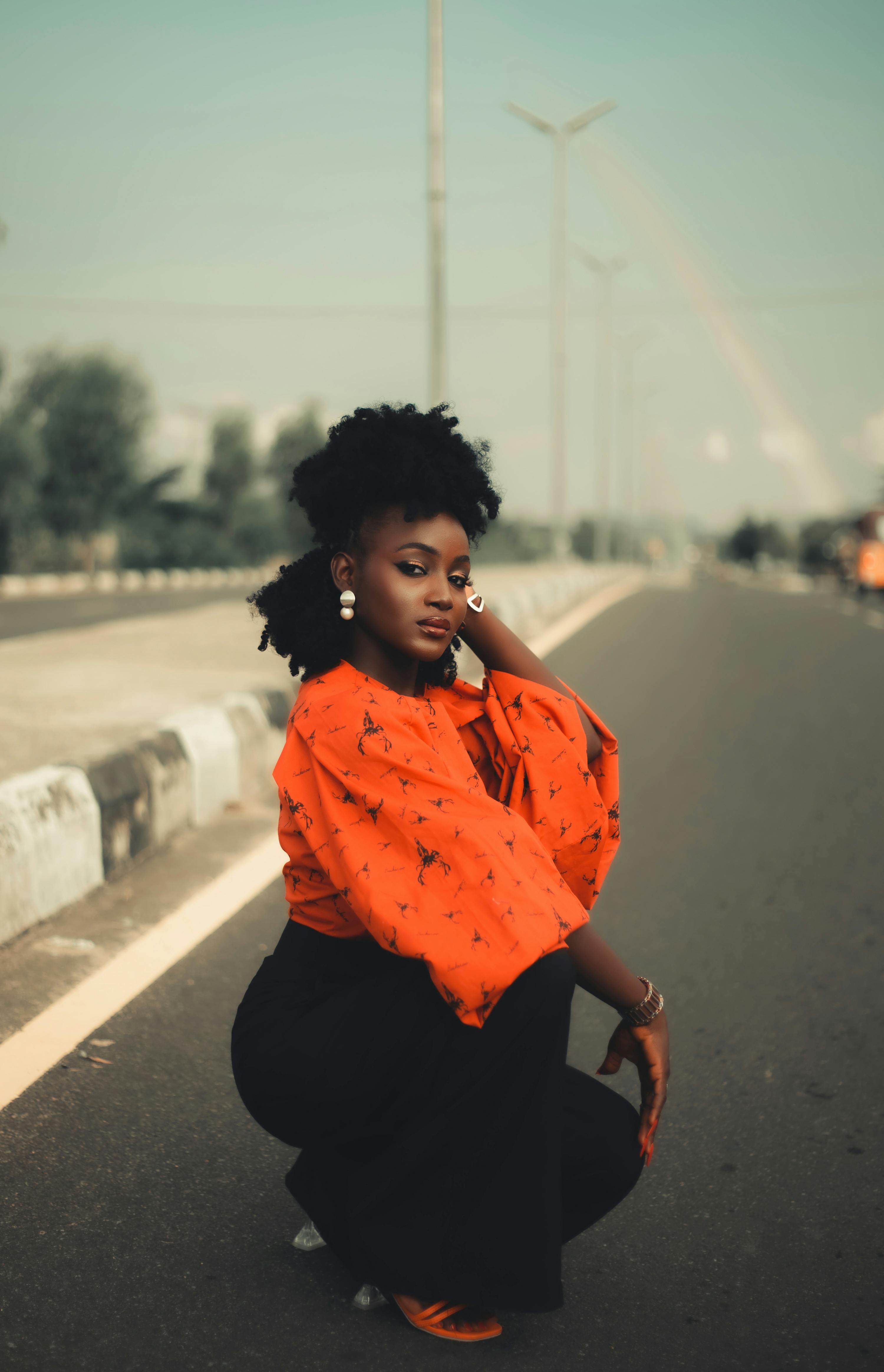 Kostenlos Eine selbstbewusste Frau hockt auf einer leeren Straße in der Stadt und präsentiert urbanen Streetstyle. Stock-Foto