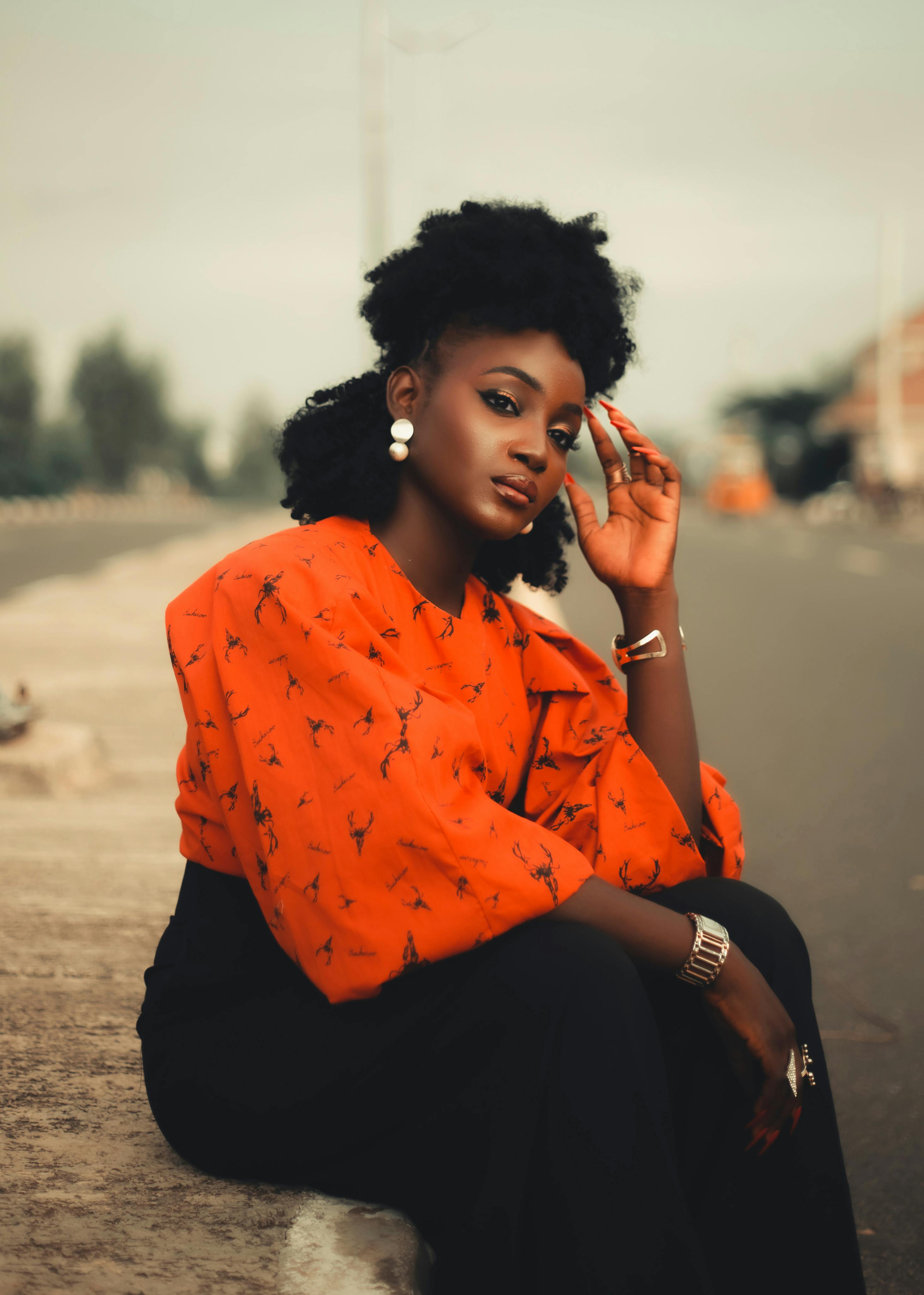 Gratis Stilfuld kvinde sidder udendørs i et livligt rødt outfit om dagen. Lagerfoto