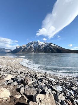 A breathtaking winter landscape with a frozen lake and majestic snow-capped mountain peaks.