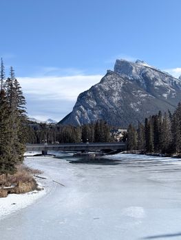 Beautiful winter landscape photo featuring Mount Rundle and a frozen river in Banff, Canada.