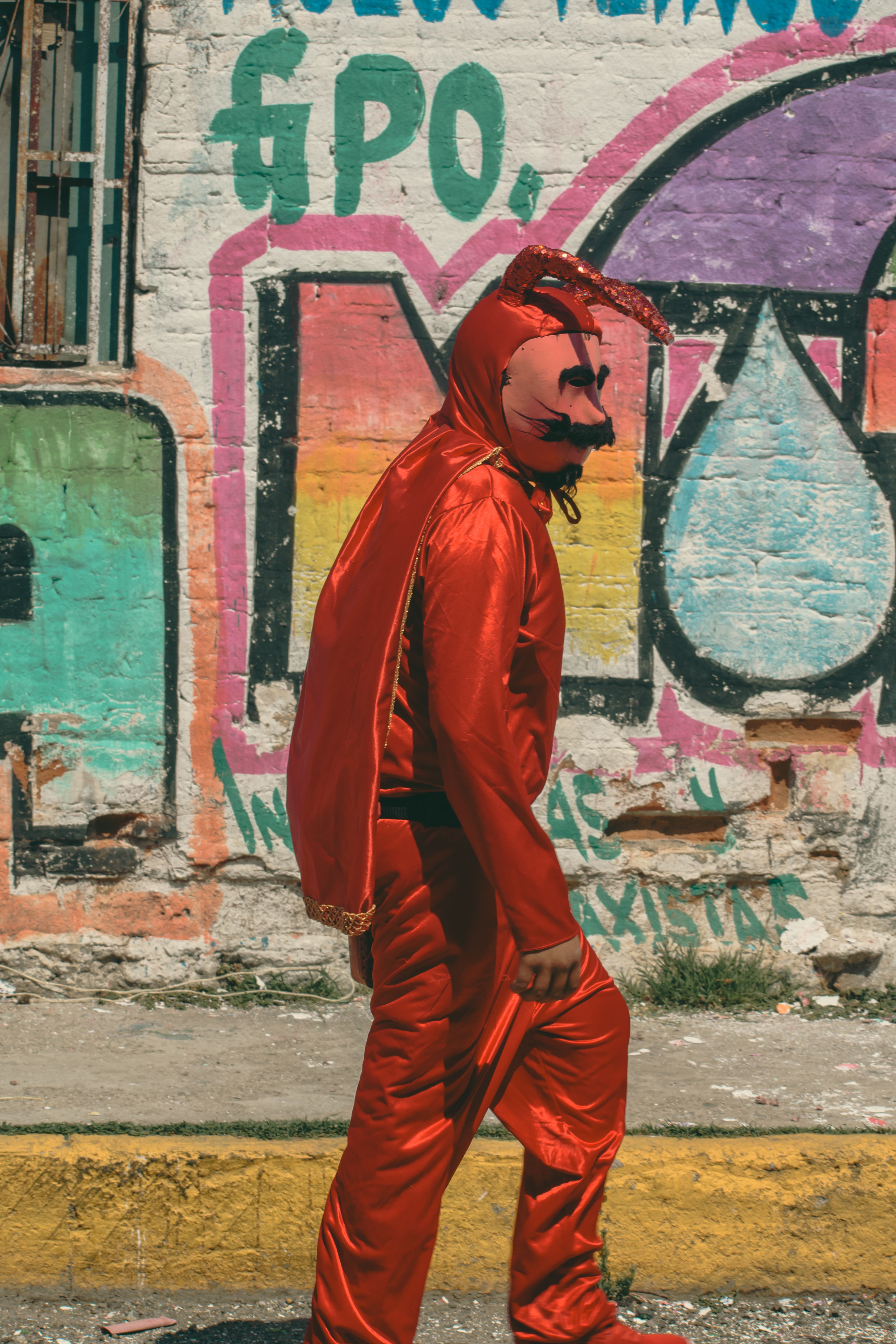 Person in Red Devil Costume Walking by Graffiti Wall · Free Stock Photo