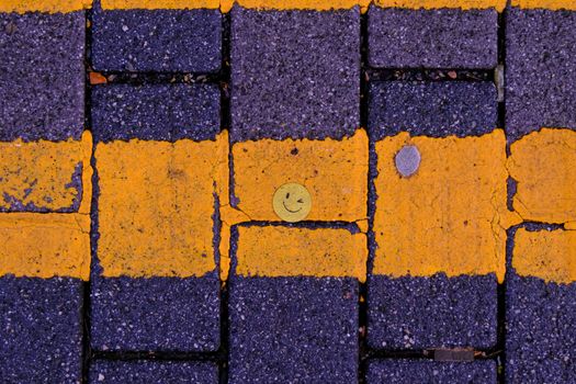 A small yellow smiley face contrasts with the cobblestones on a London street.