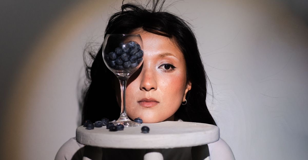 Creative portrait of a woman with blueberries and glass reflection, blending art and food for a unique visual effect. - Evidence evidence guide for blueberry visual performance randomized trial