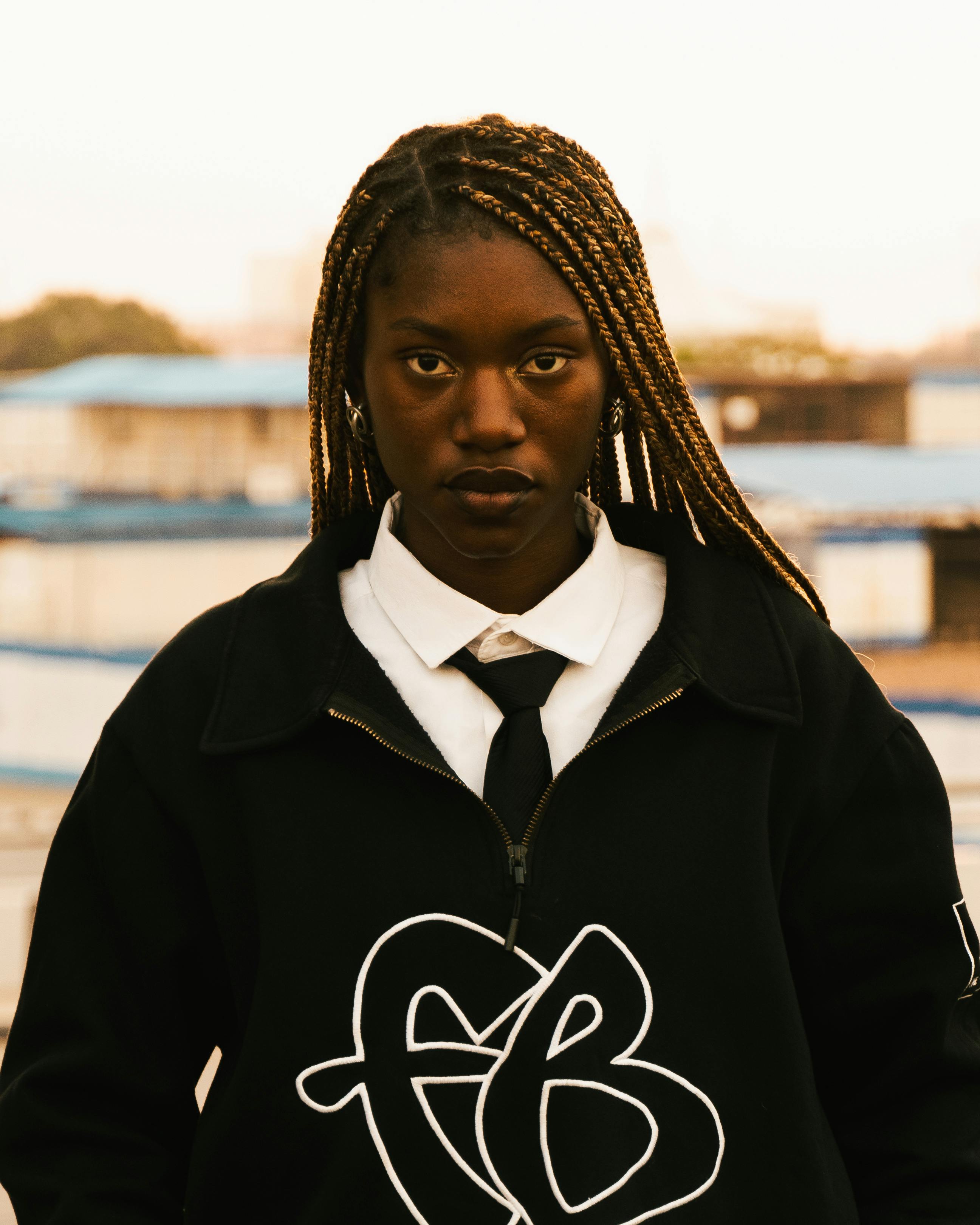 Striking portrait of a young woman with braided hair in an urban setting, exuding confidence.