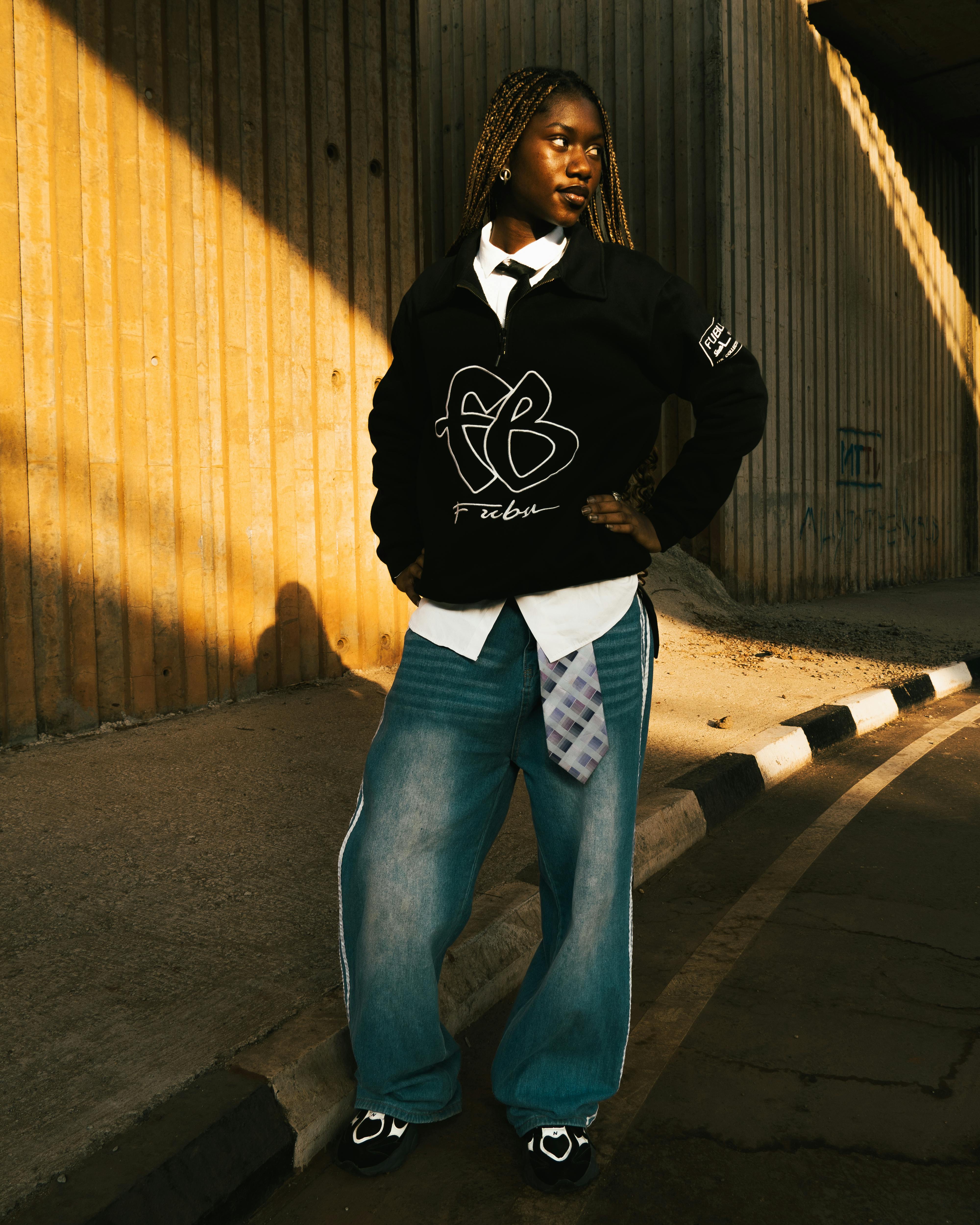 Portrait of a stylish young adult posing under an overpass with urban fashion.