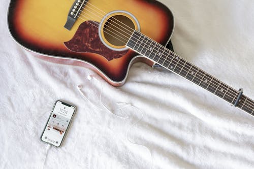 Red and Black Acoustic Guitar next to Smart Phone