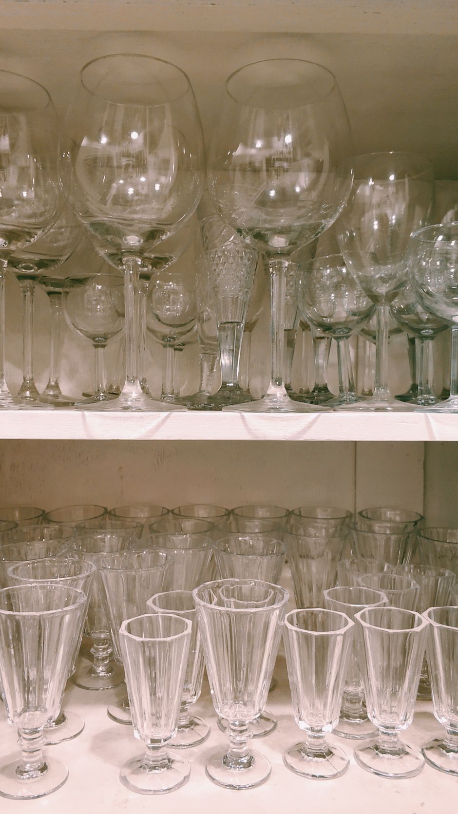 An organized display of various elegant glassware on shelves. Perfect for dining decors.