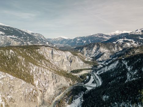A breathtaking aerial view of the snow-covered Swiss Alps, showcasing rugged terrain and winding rivers.