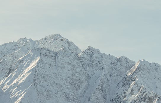 Stunning view of snow-covered mountain peaks under a clear winter sky, perfect for travel and nature lovers.