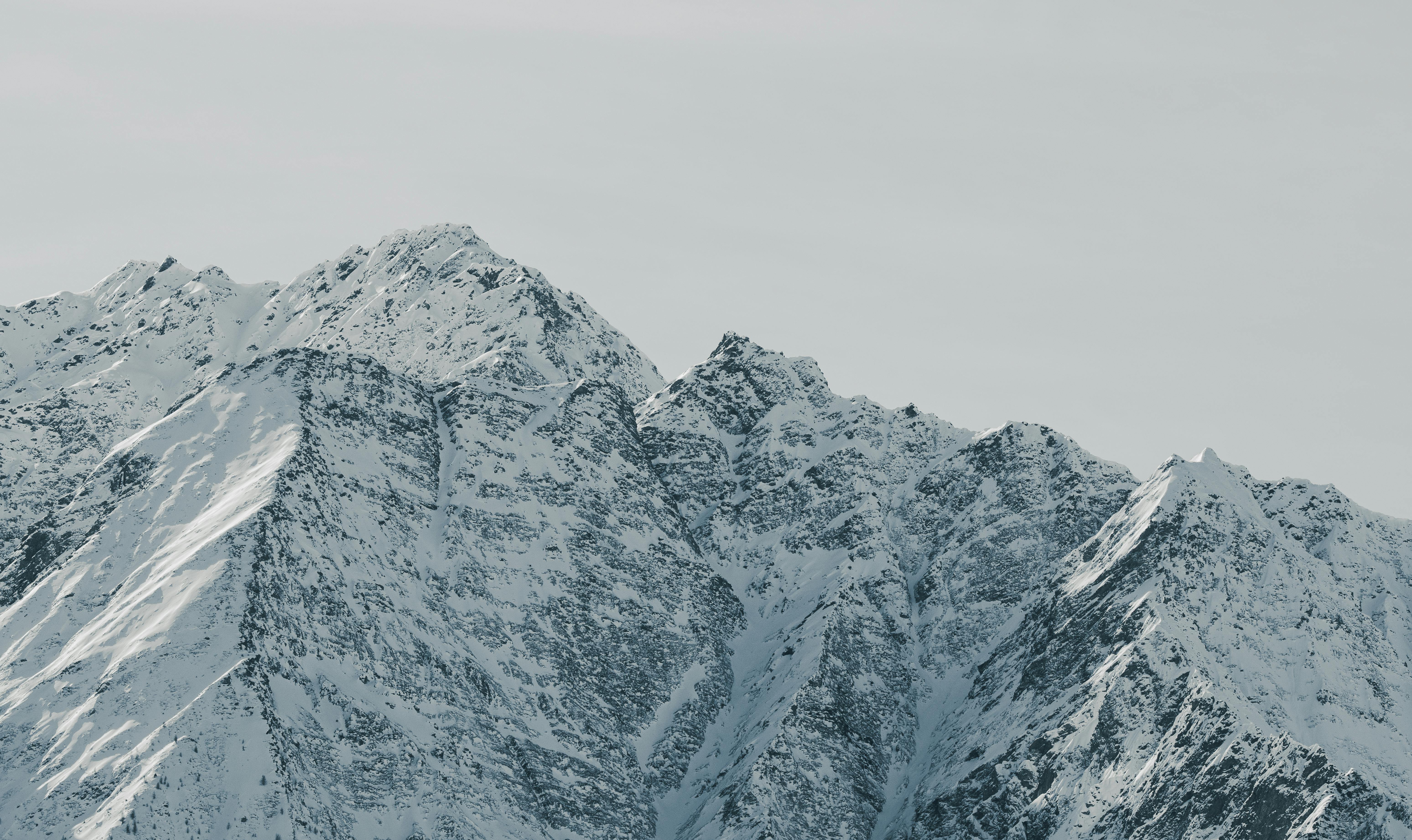 бесплатная Захватывающий вид на заснеженные горные вершины на фоне чистого зимнего неба. Стоковое фото