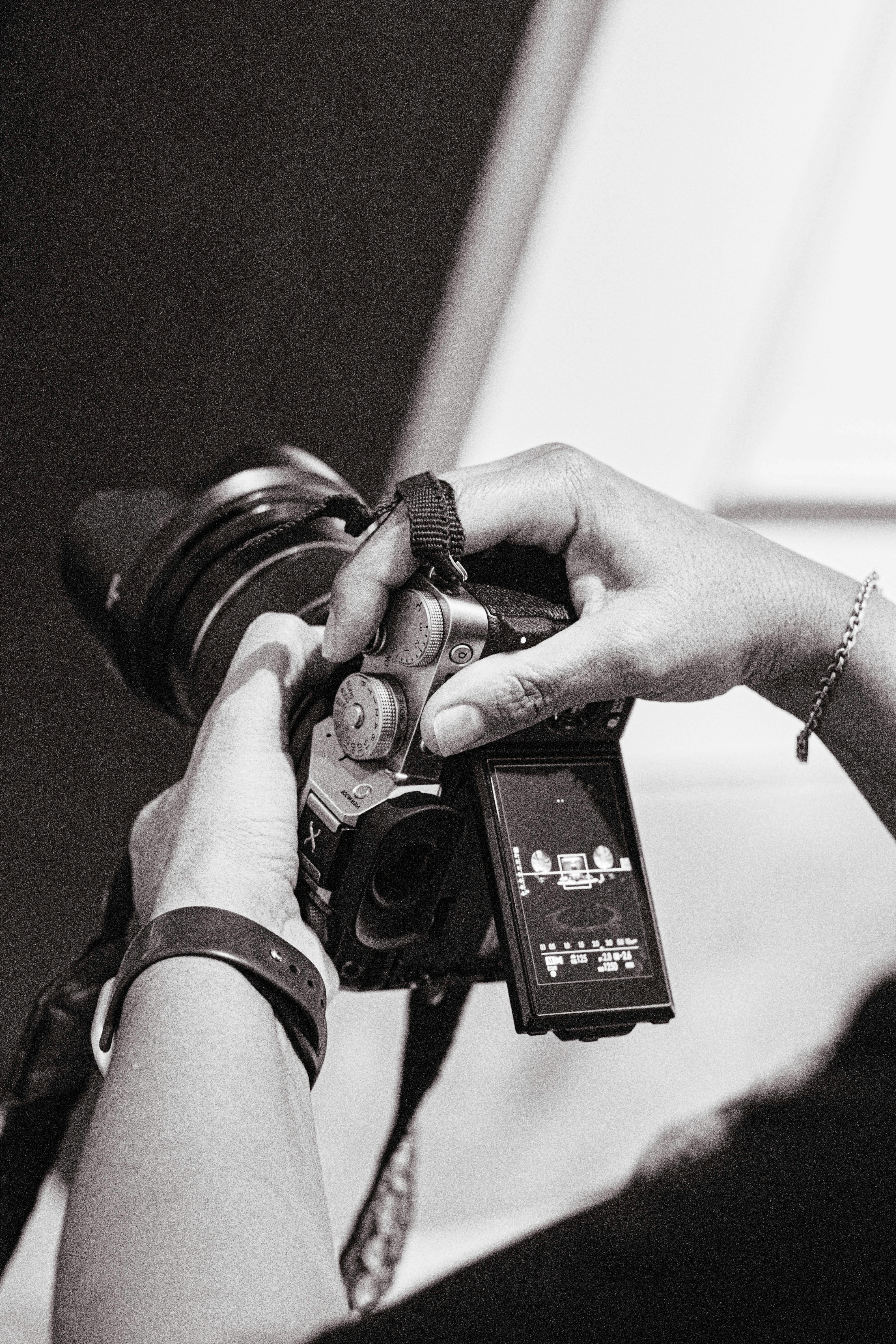 Gratis Svart-hvitt-bilde av en fotograf som justerer kamerainnstillingene. Kunstnerisk og teknisk fokus. Arkivbilde