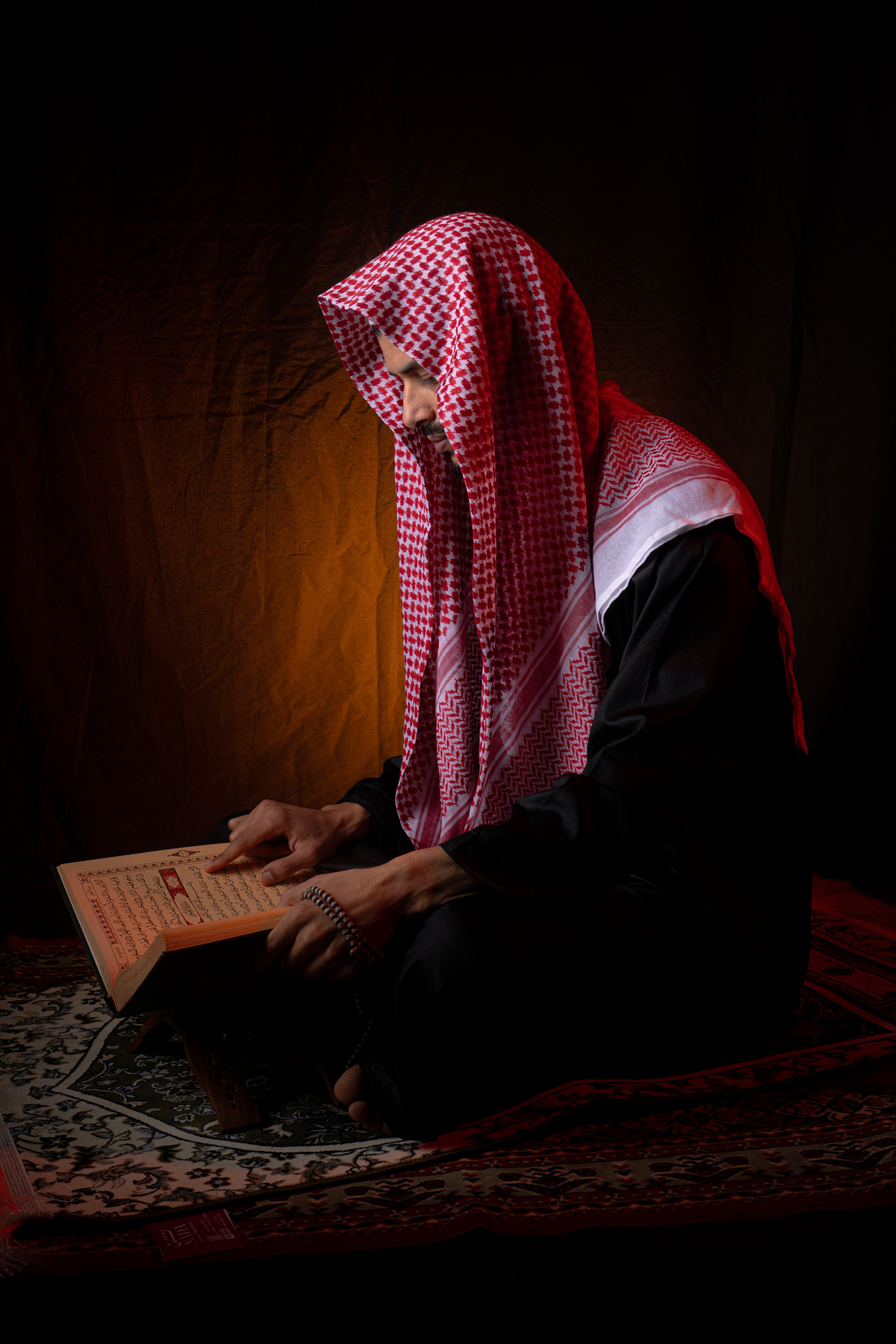 Man in Traditional Attire Reading a Holy Book