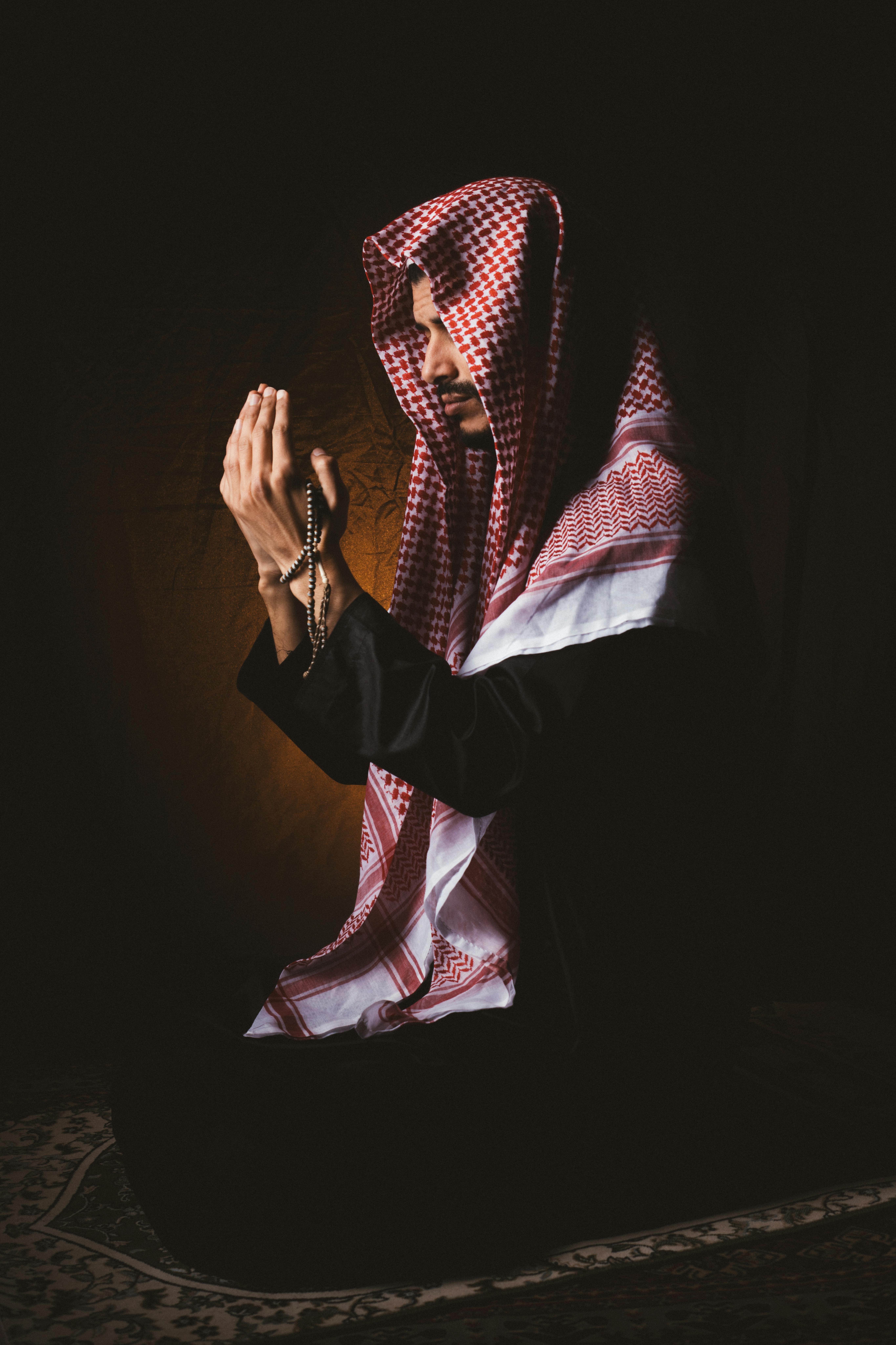Free Man in traditional Middle Eastern attire praying, holding prayer beads. Stock Photo