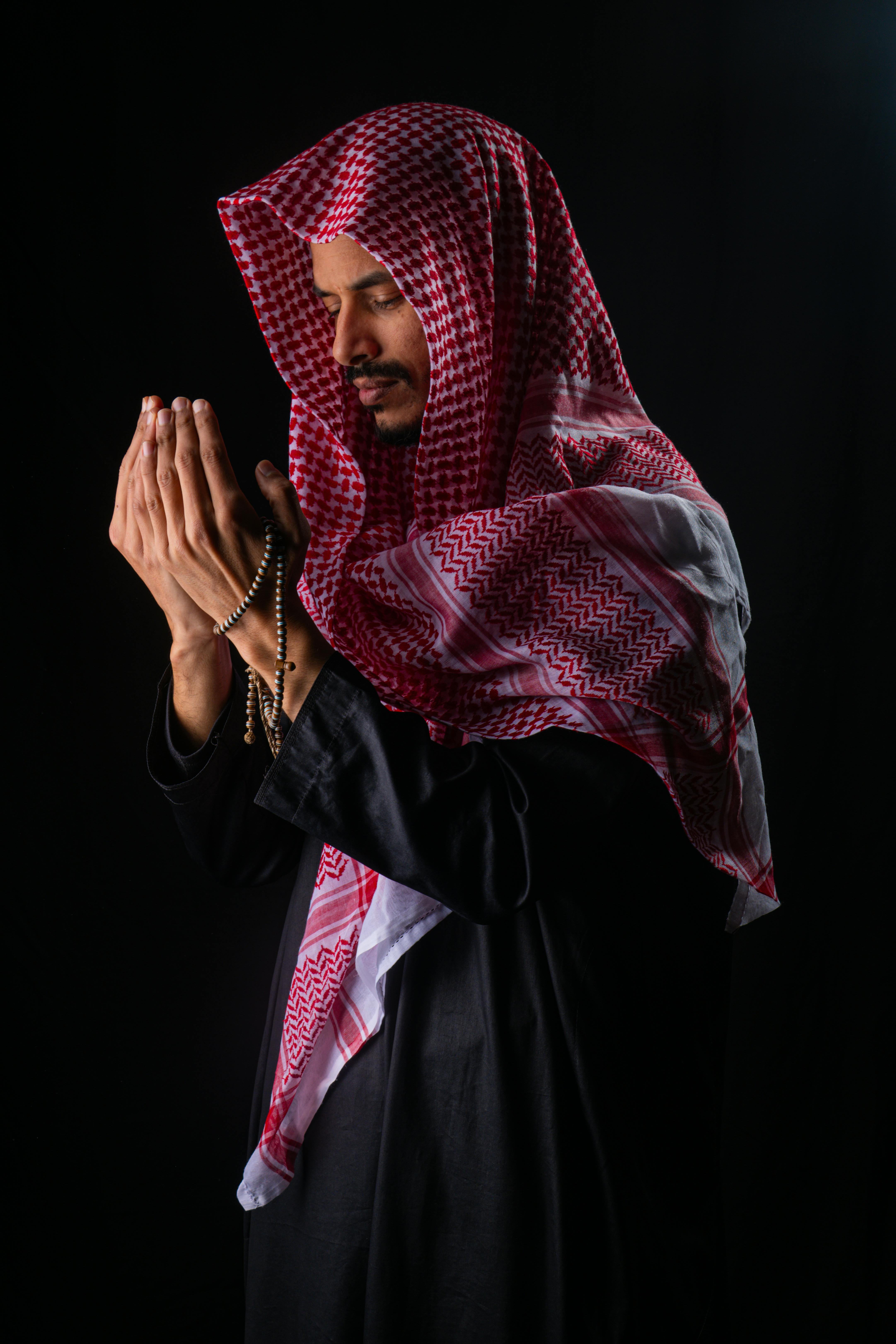 Gratis Mand i traditionelt klædedragt beder med rosenkransperler i mørke omgivelser. Lagerfoto