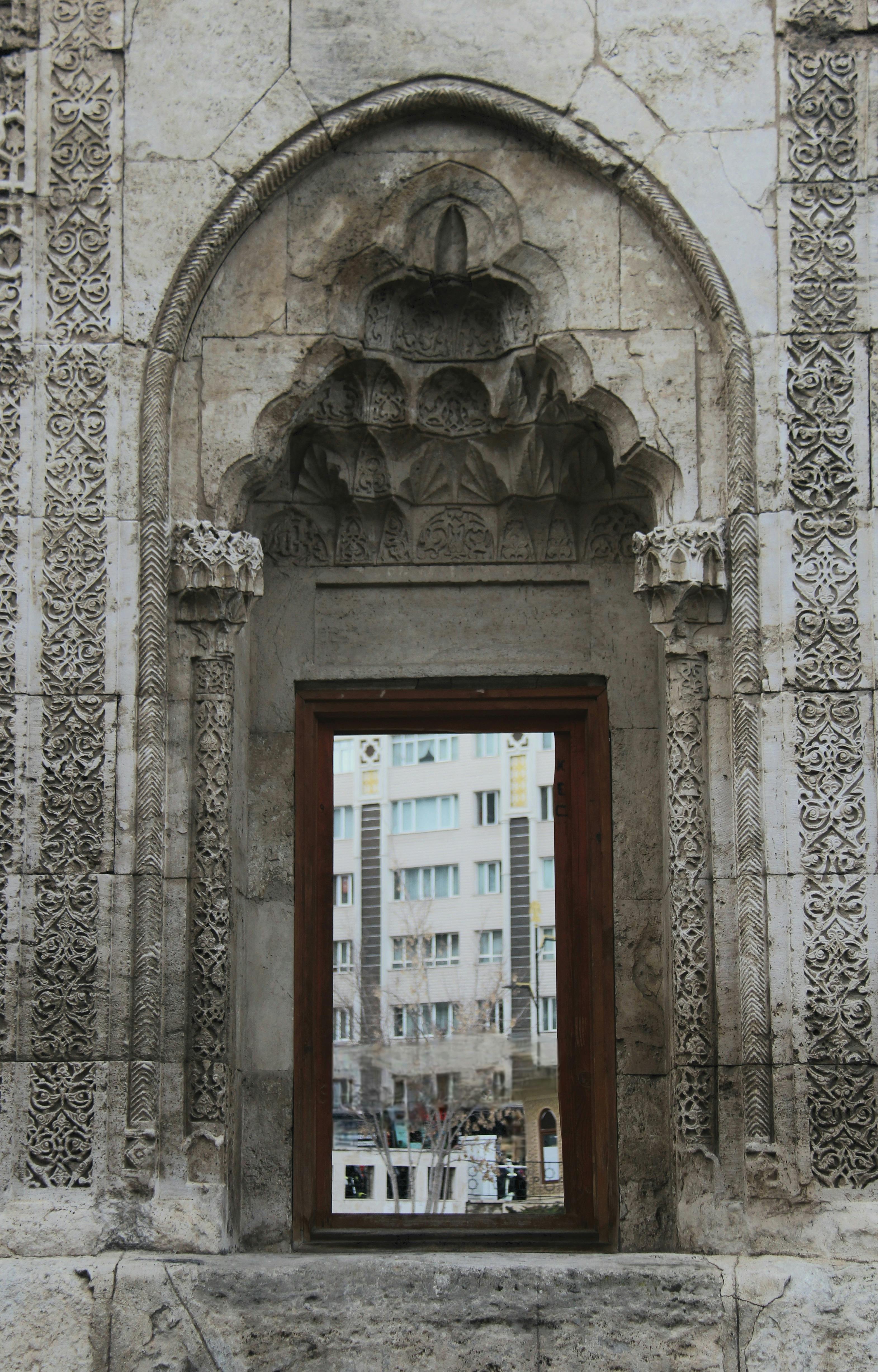 無料 都市の建物の景色を縁どる、精巧に彫刻された石のアーチ。 写真素材