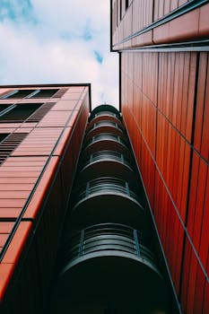 在多云的天空下，现代红色建筑以低视角引人注目